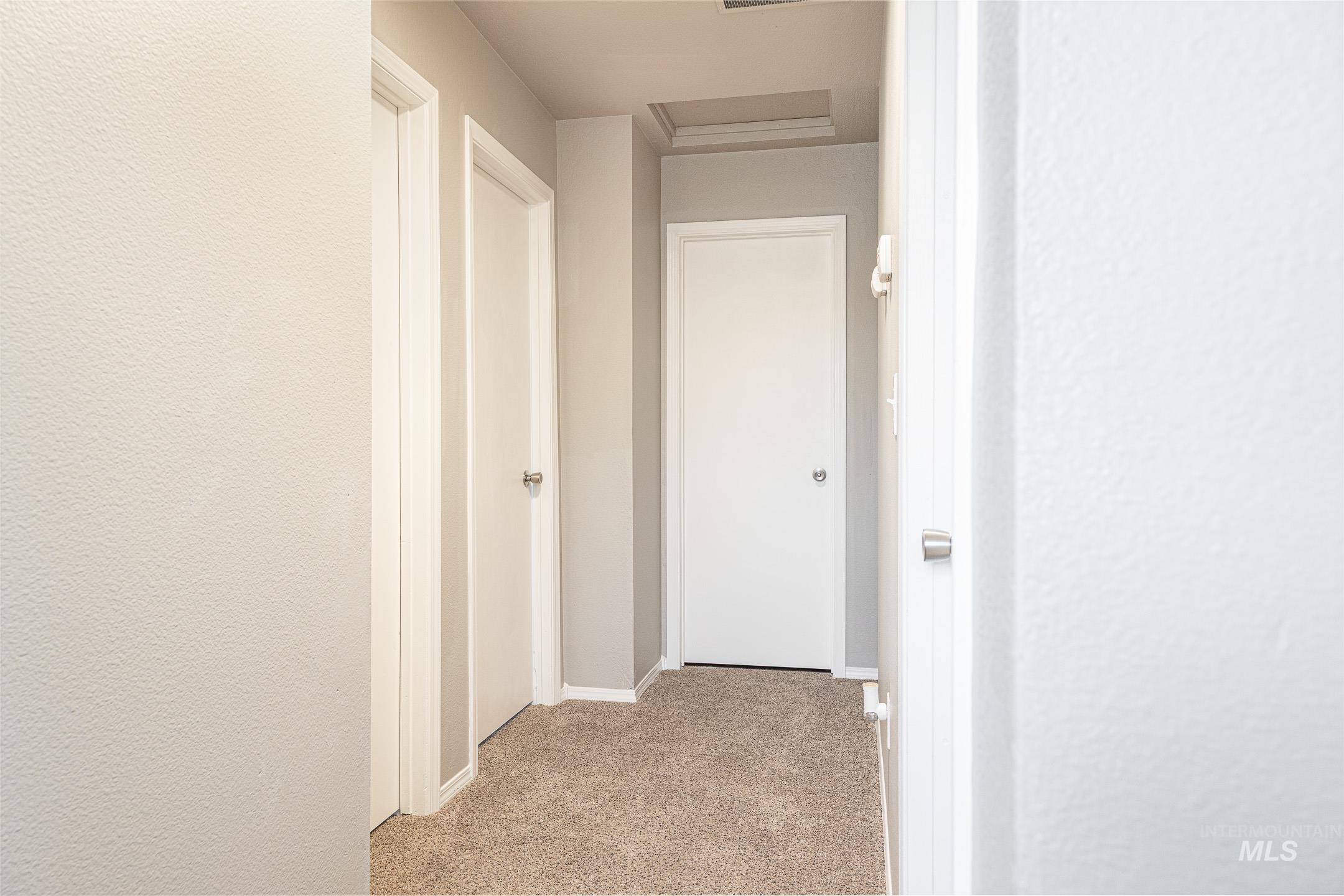 Corridor with light colored carpet and a textured wall