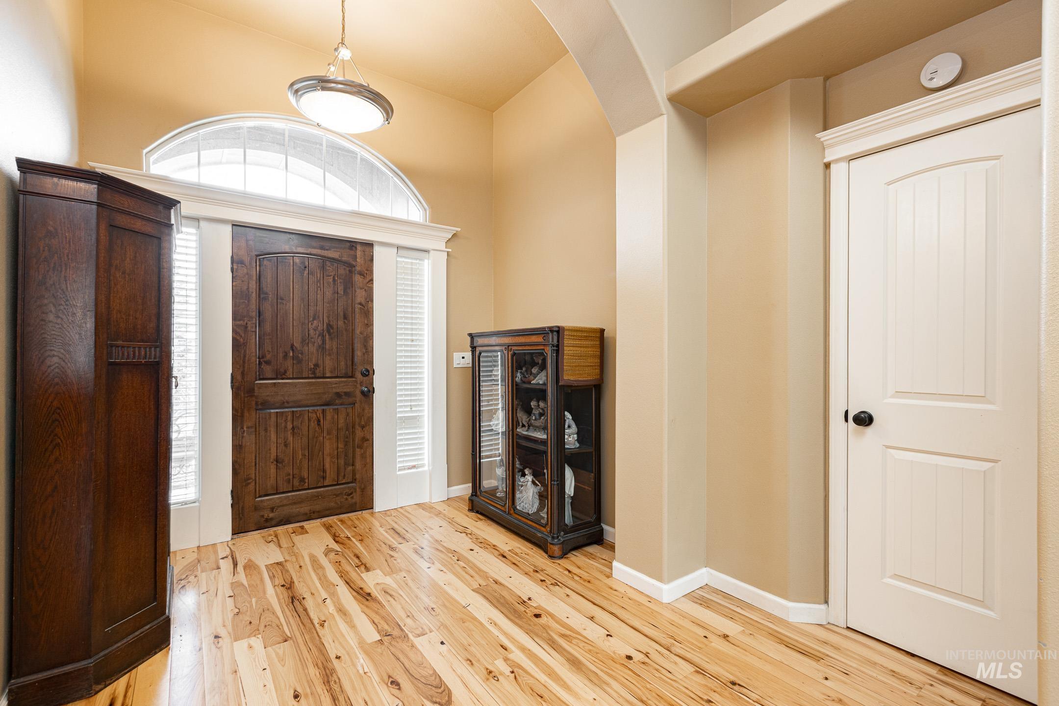 Foyer with arched walkways and light wood finished floors