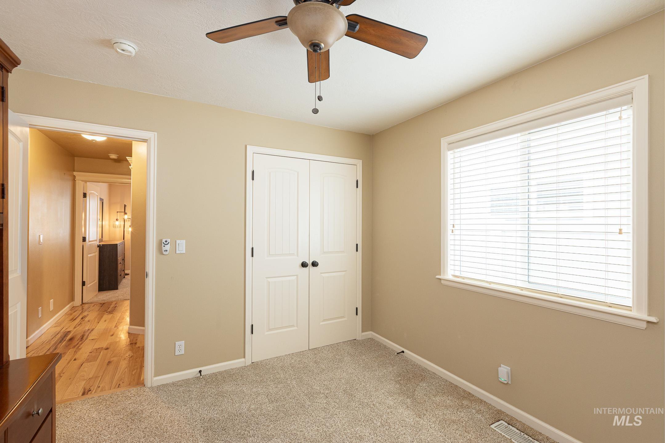 Unfurnished bedroom with light carpet, a closet, and a ceiling fan