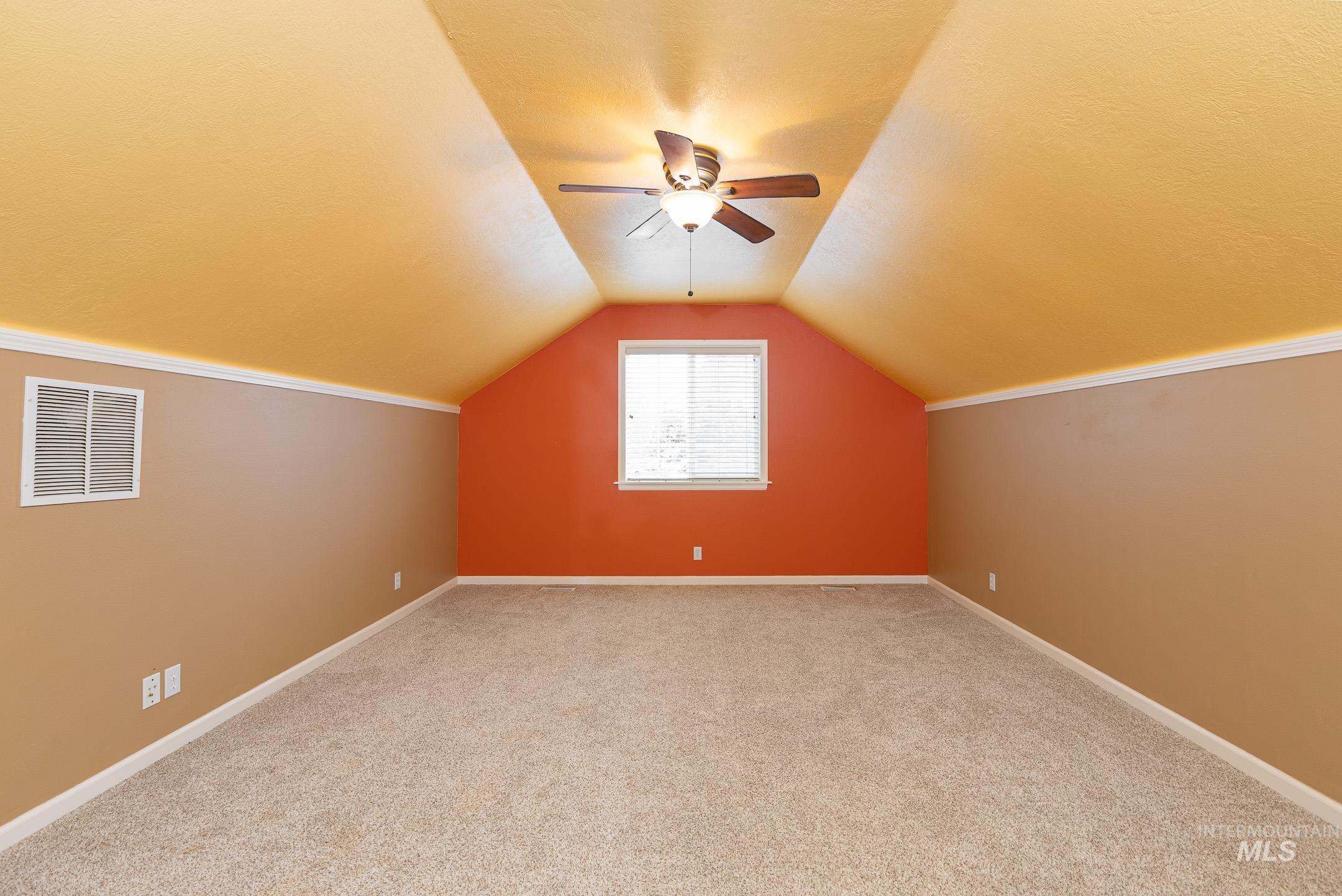 Additional living space with light colored carpet, ceiling fan, vaulted ceiling, and a textured ceiling