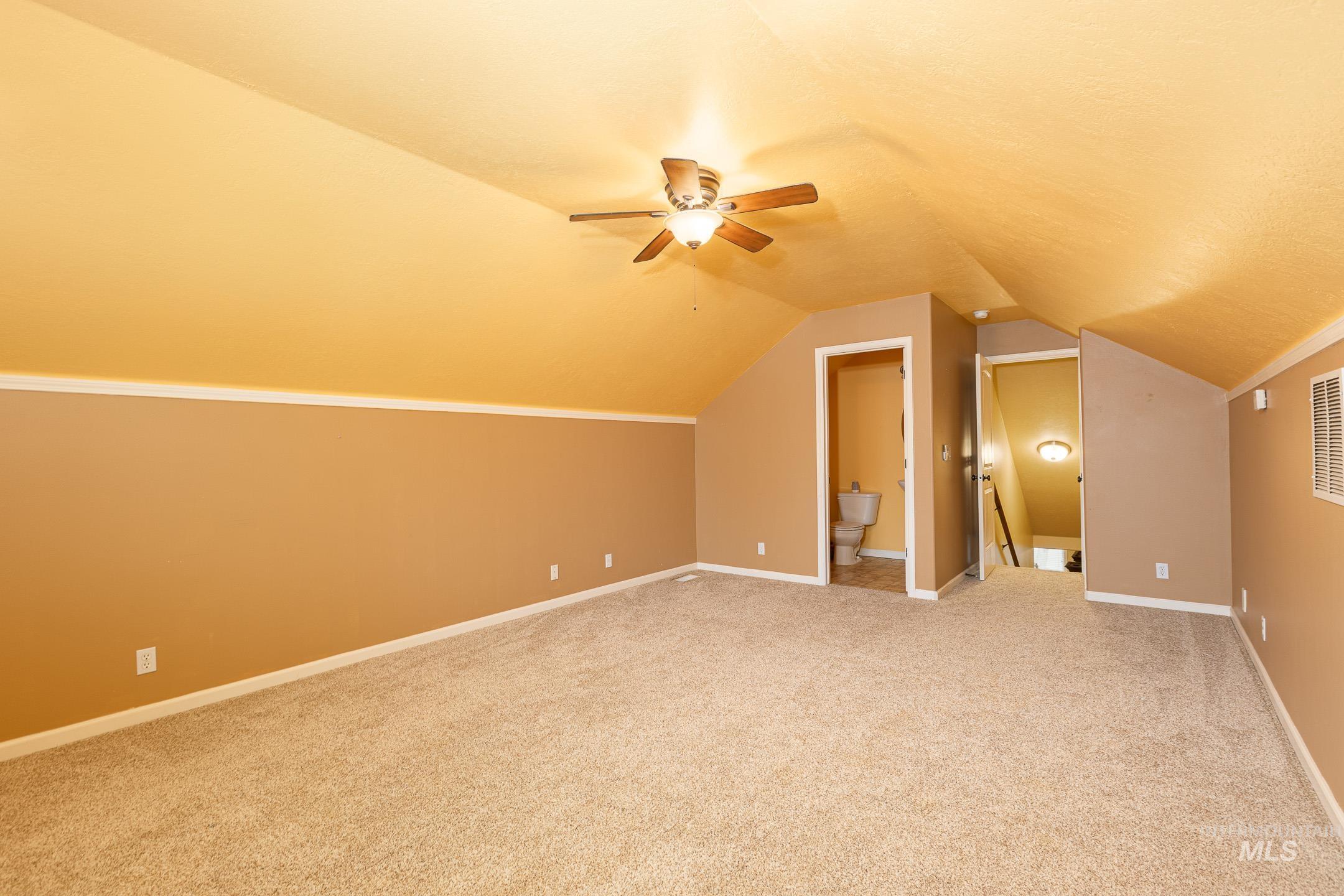 Bonus room featuring light carpet, vaulted ceiling, and ceiling fan