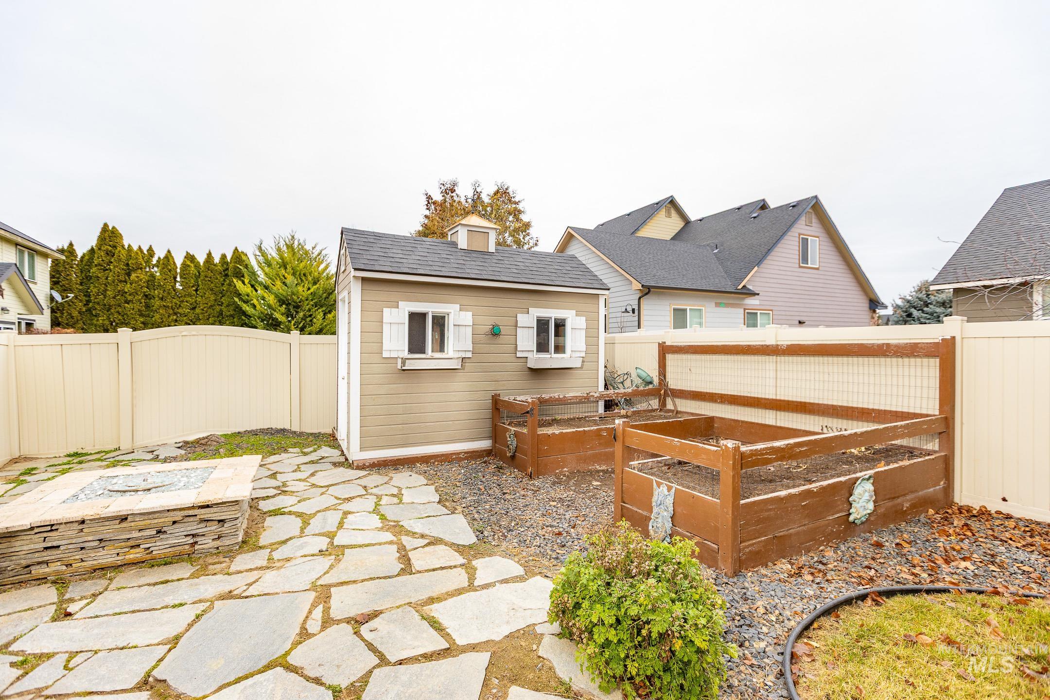 Rear view of property featuring an outdoor structure, a fenced backyard, a vegetable garden, and a patio