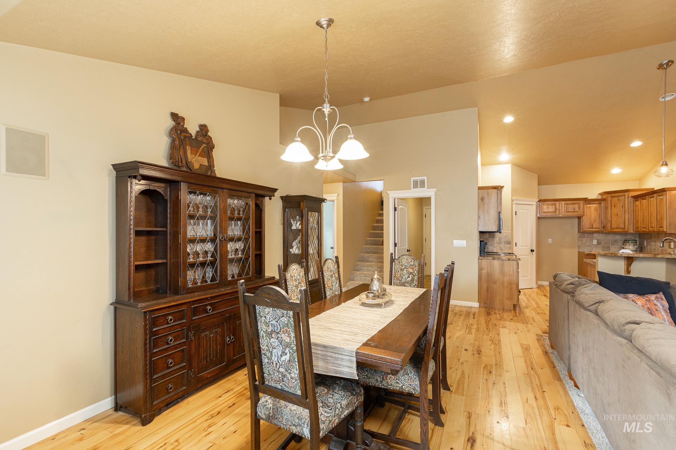 Dining space featuring stairway, light wood-type flooring, a chandelier, and recessed lighting