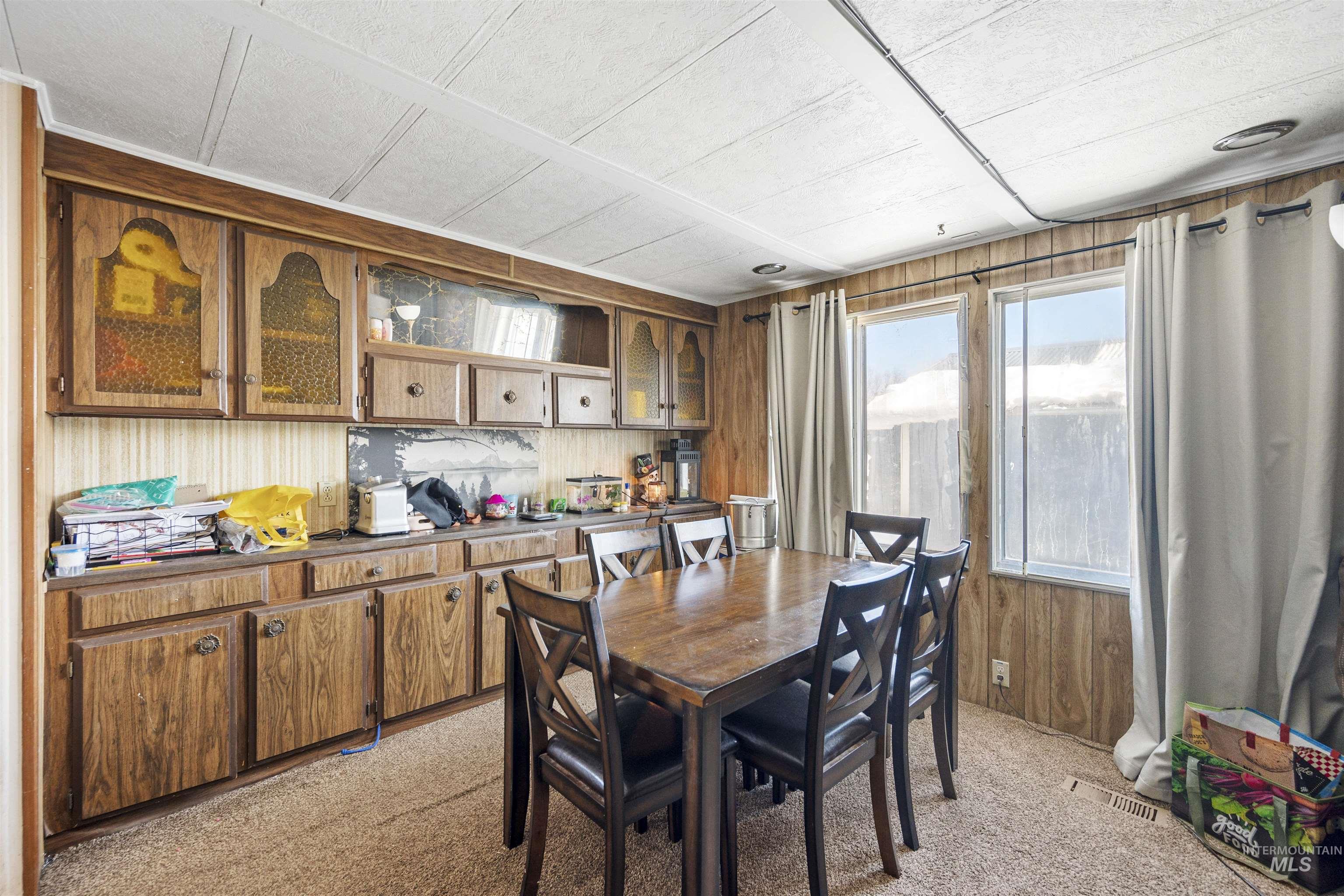 Dining area featuring light colored carpet and wood walls