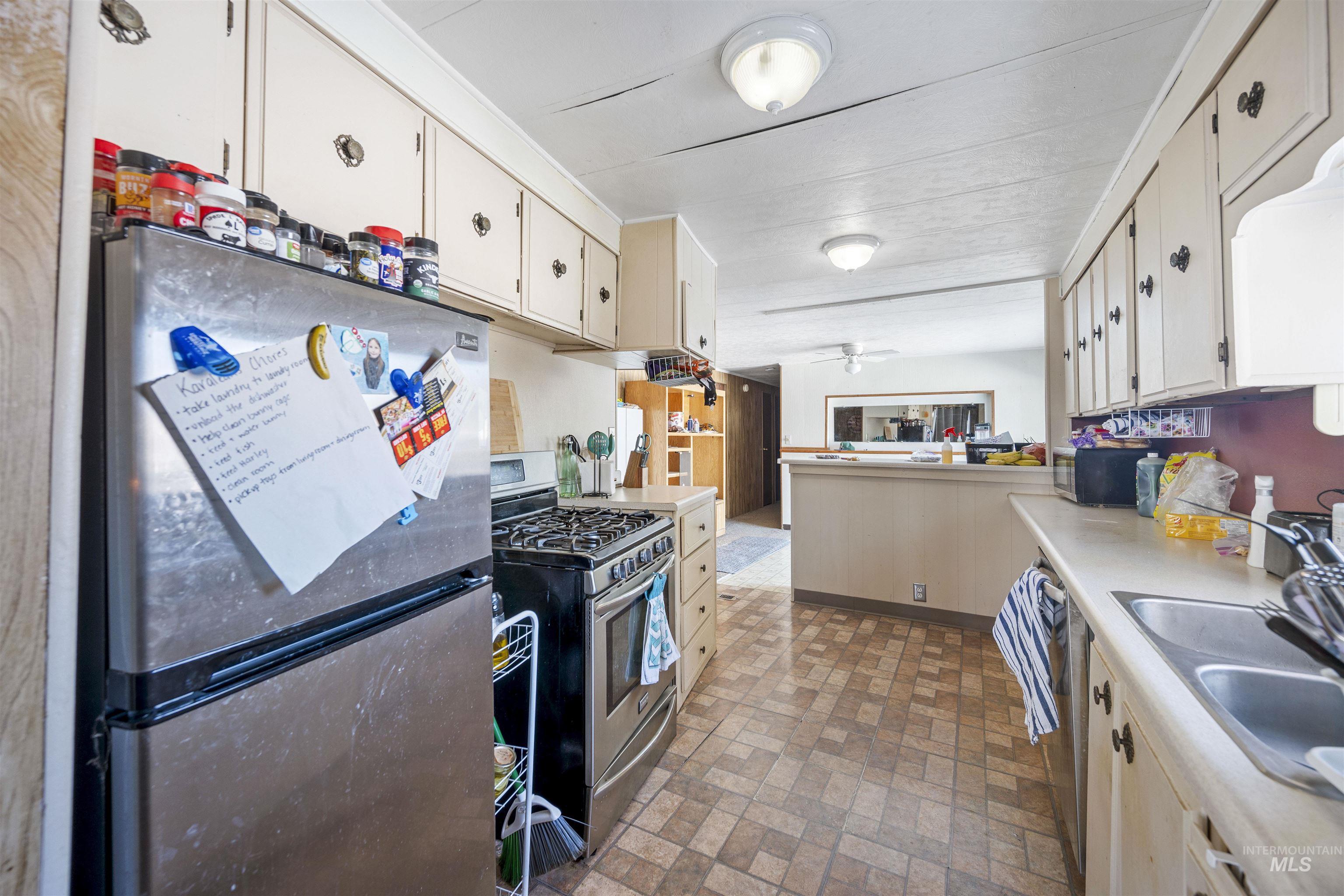 Kitchen with stainless steel appliances, brick patterned floors, light countertops, and a peninsula