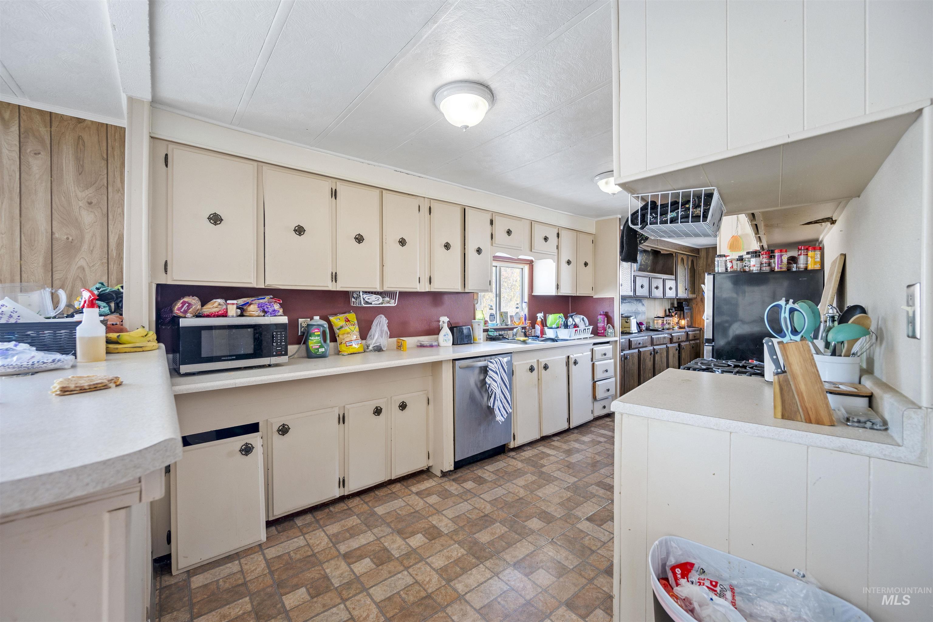 Kitchen with cream cabinets, brick patterned floors, light countertops, and stainless steel appliances