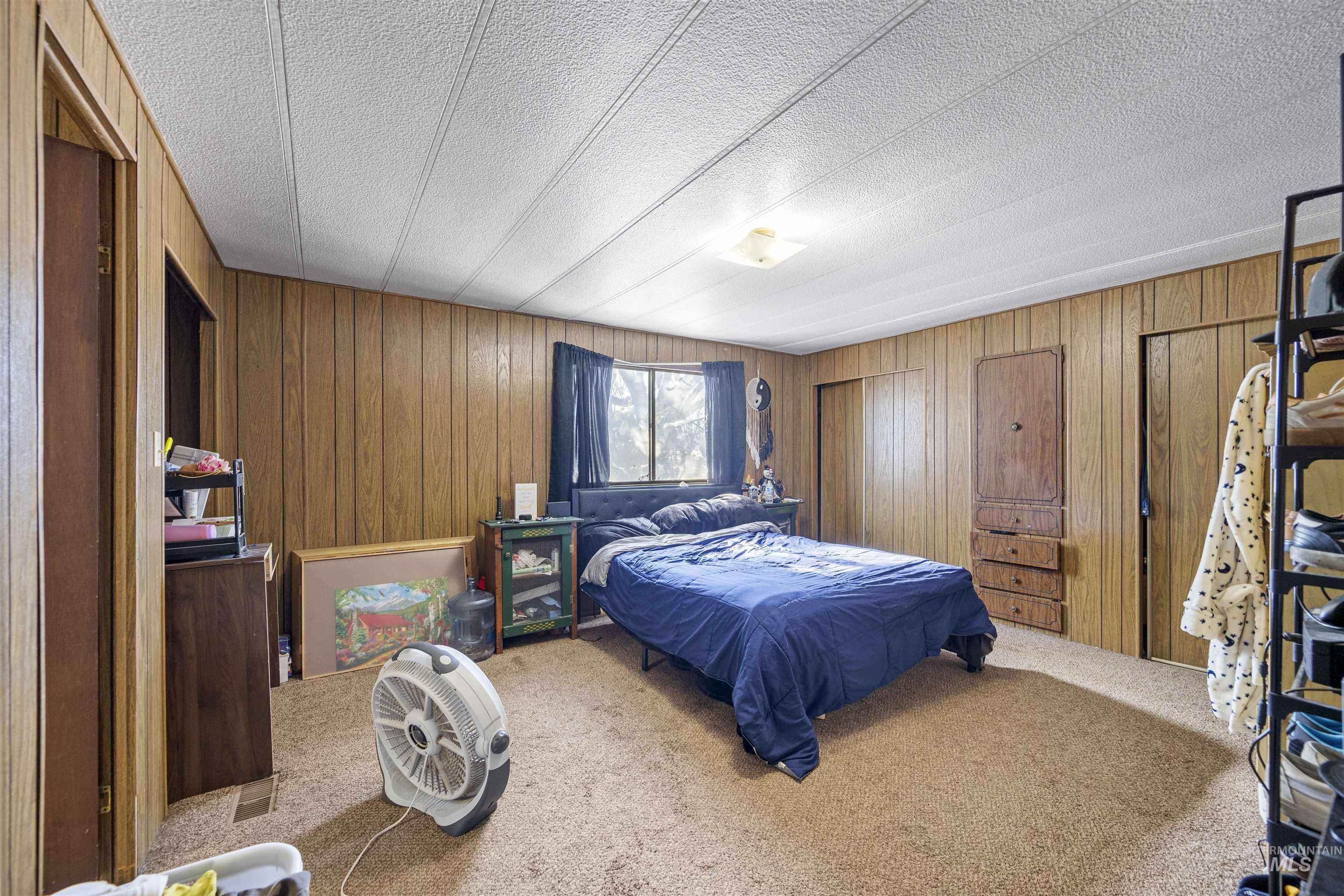 Carpeted bedroom featuring wood walls and a textured ceiling