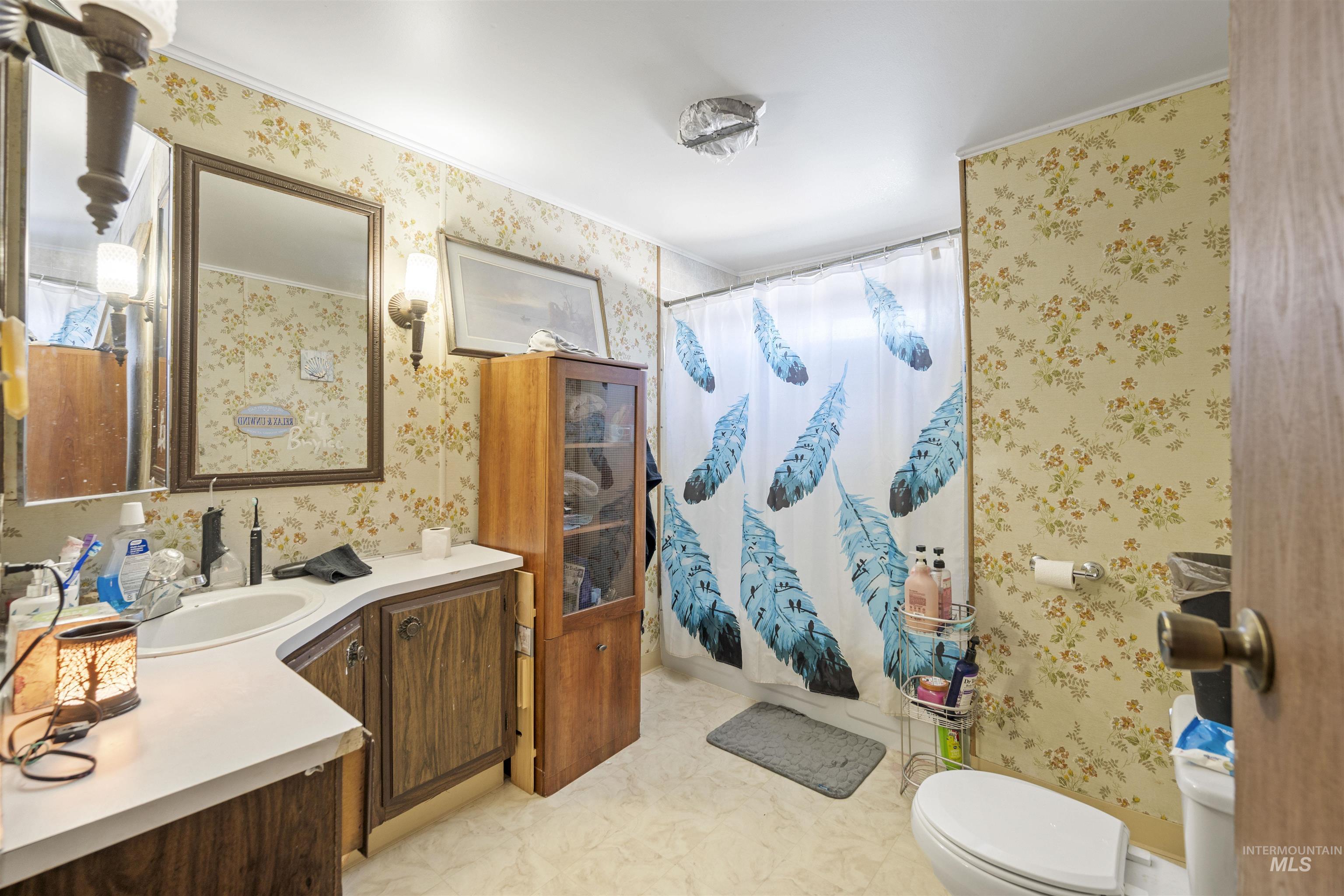 Full bath with wallpapered walls, vanity, a shower with curtain, and light floors