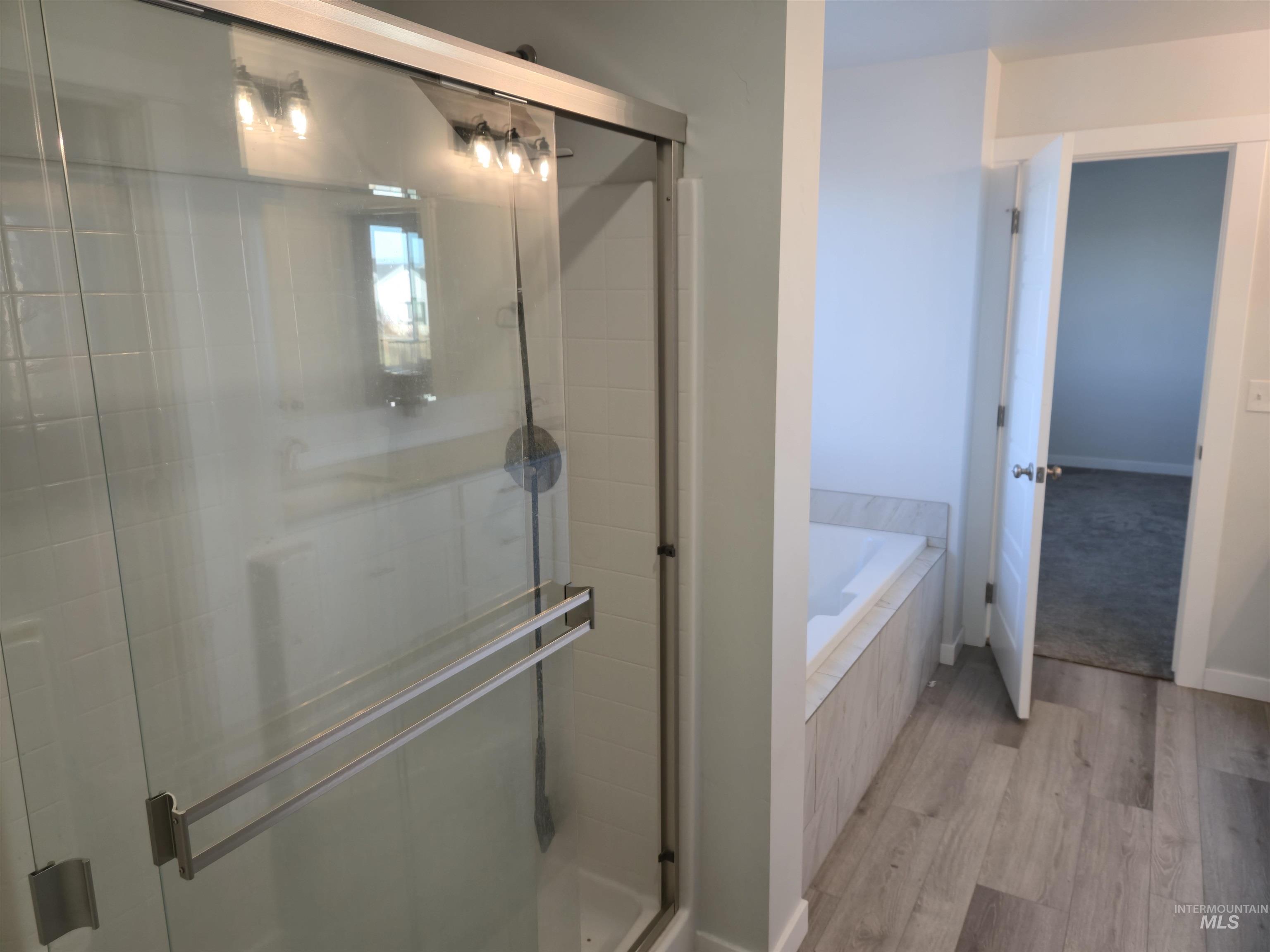 Bathroom featuring a shower stall, a bath, and light wood finished floors
