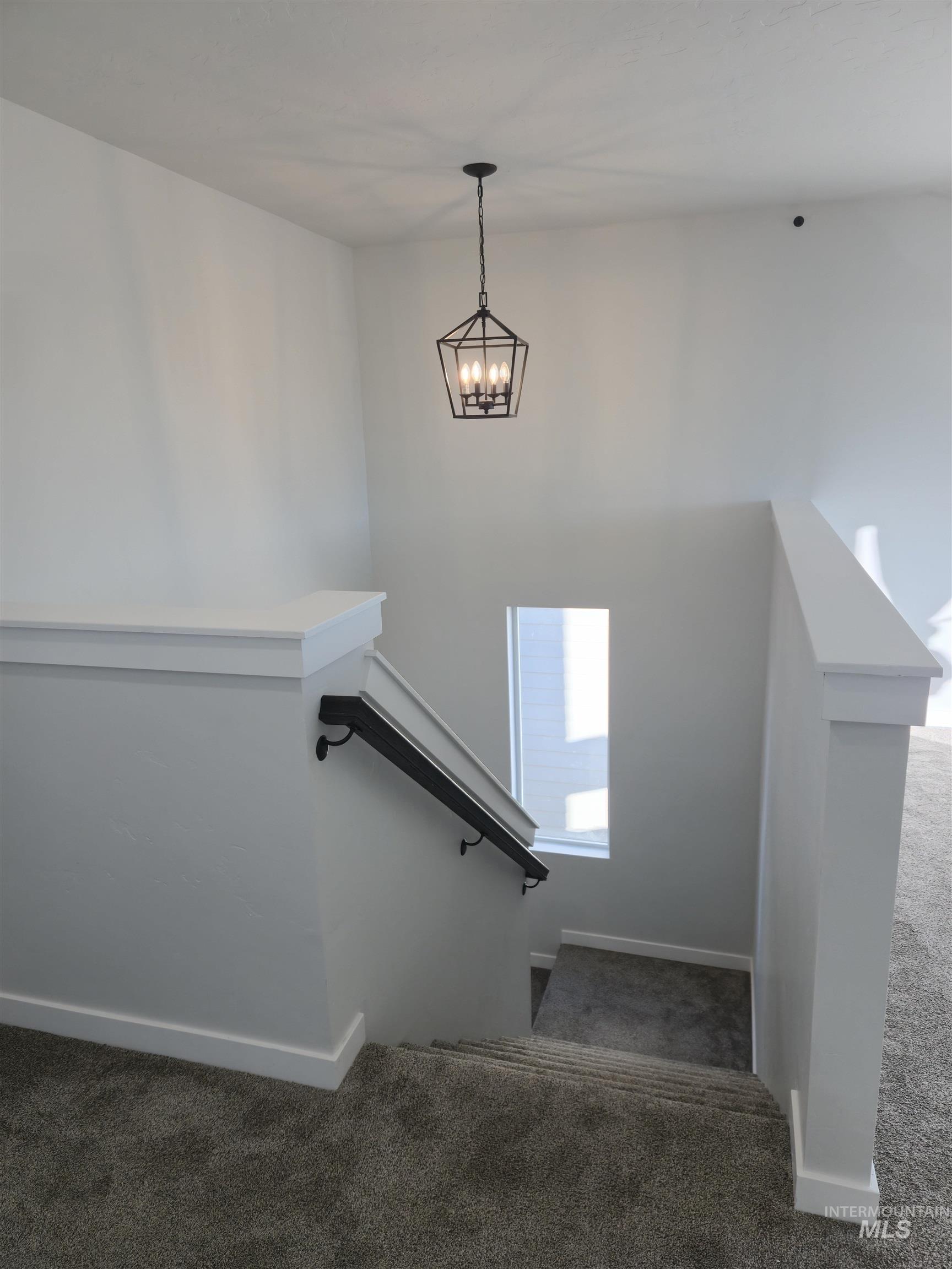Stairway with carpet flooring and a chandelier