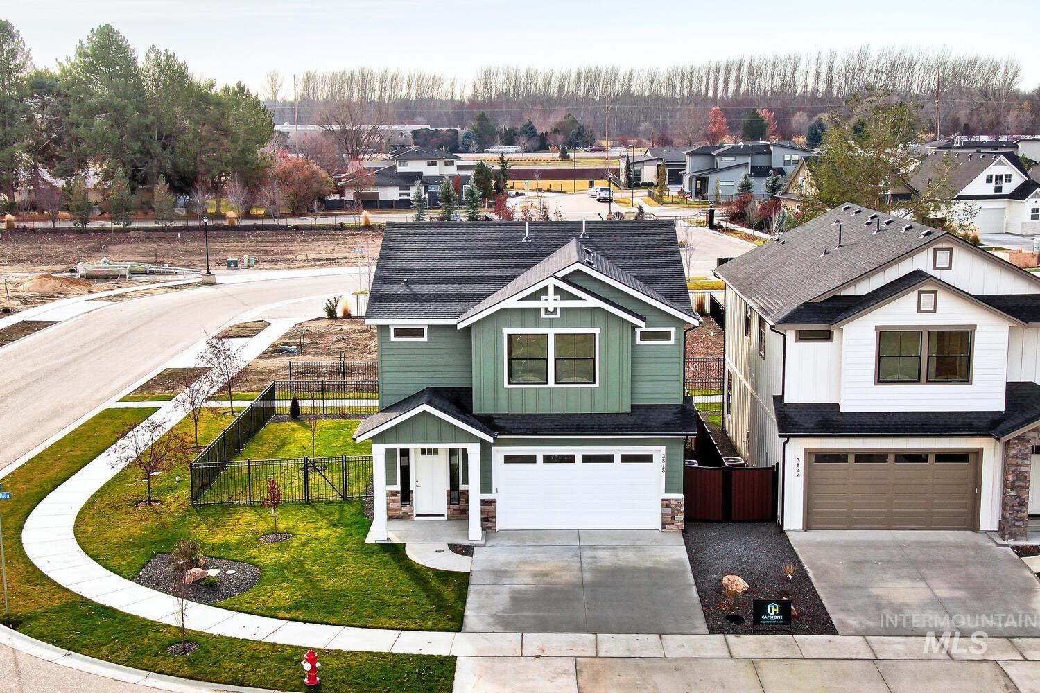 View of front of home with stone siding, driveway, a garage, a residential view, and a gate