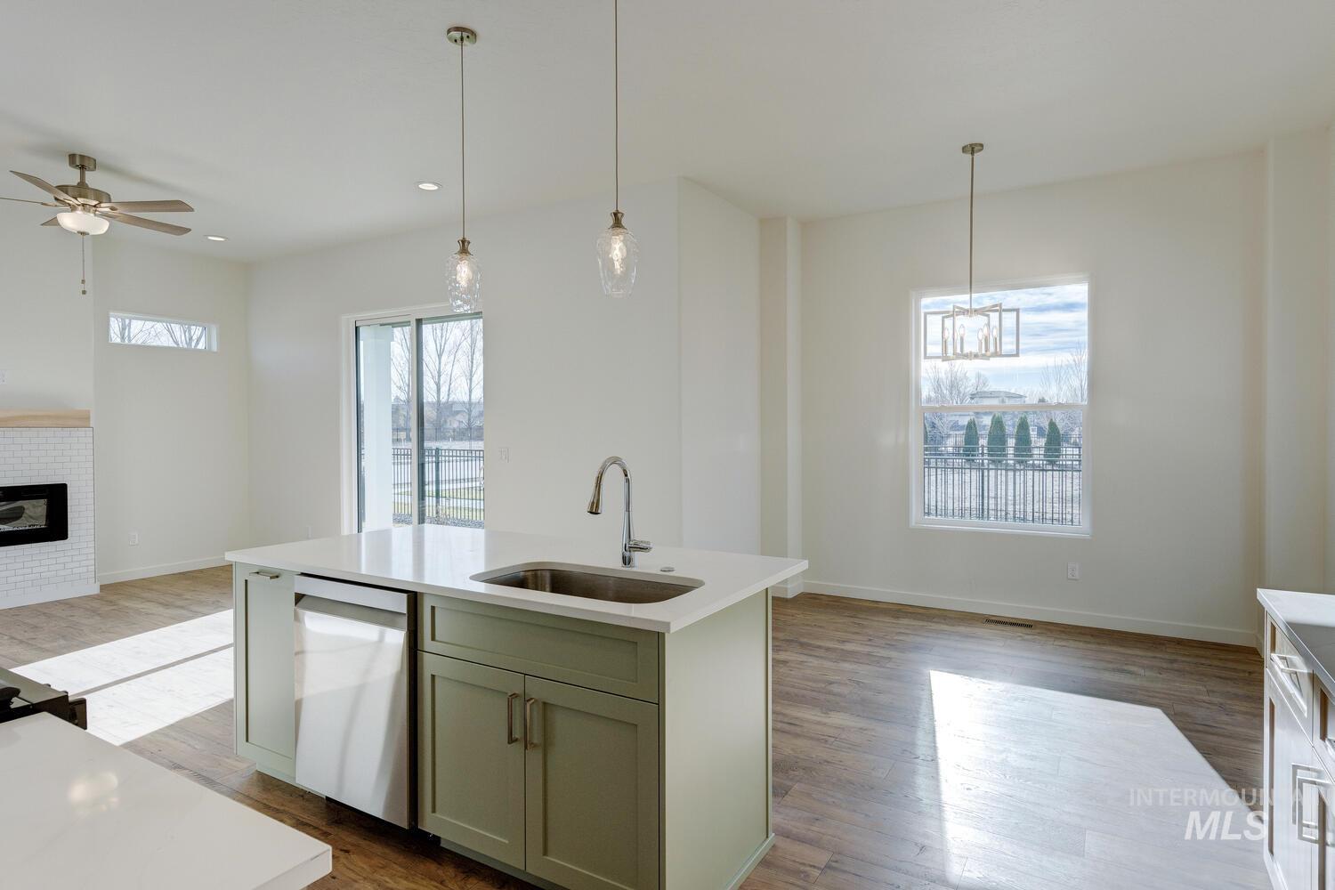 Kitchen featuring open floor plan, decorative light fixtures, dishwasher, dark wood finished floors, and an island with sink