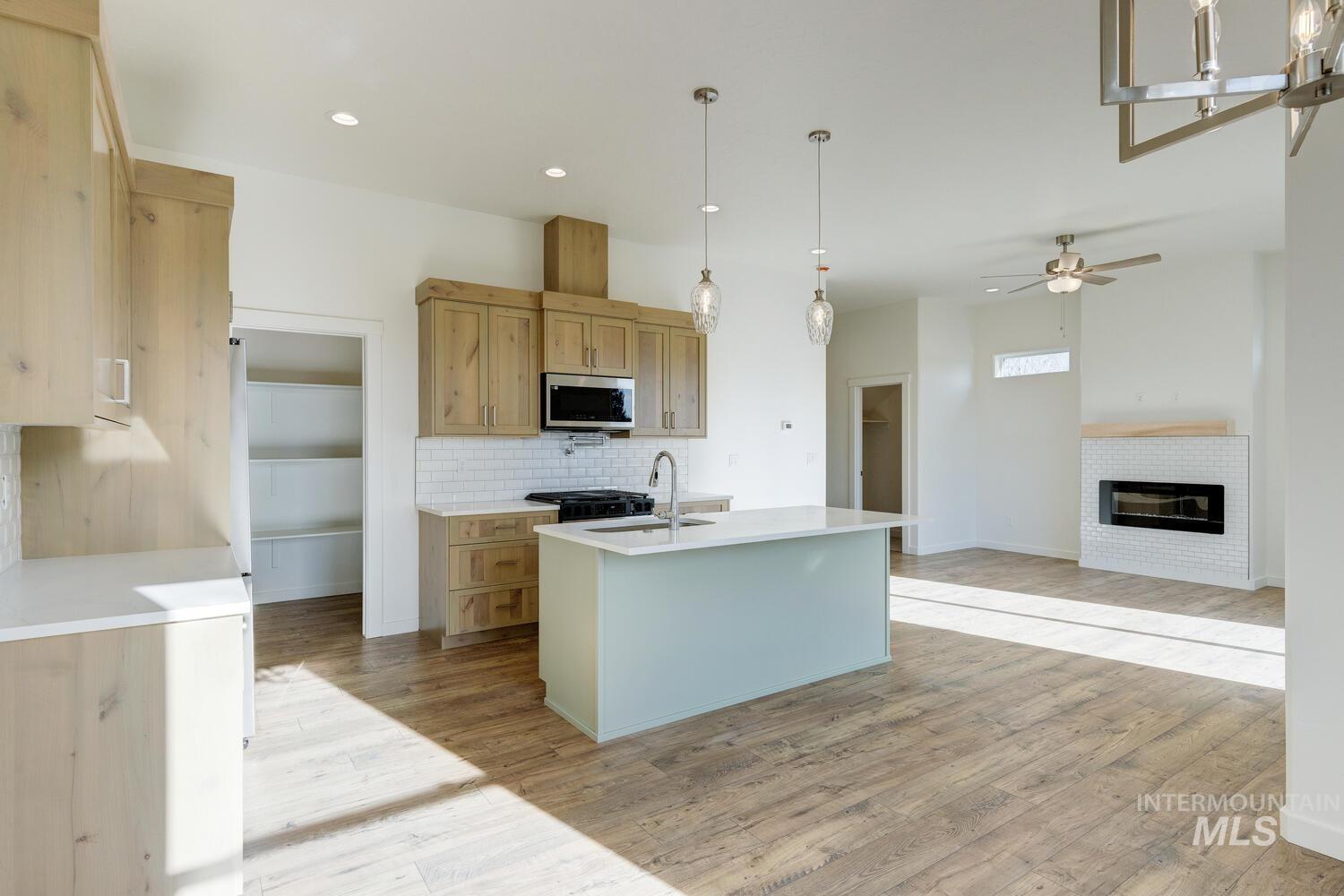 Kitchen with decorative light fixtures, decorative backsplash, an island with sink, light wood-style flooring, and recessed lighting