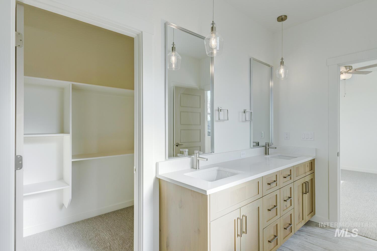 Full bath with light carpet, double vanity, a ceiling fan, and a walk in closet