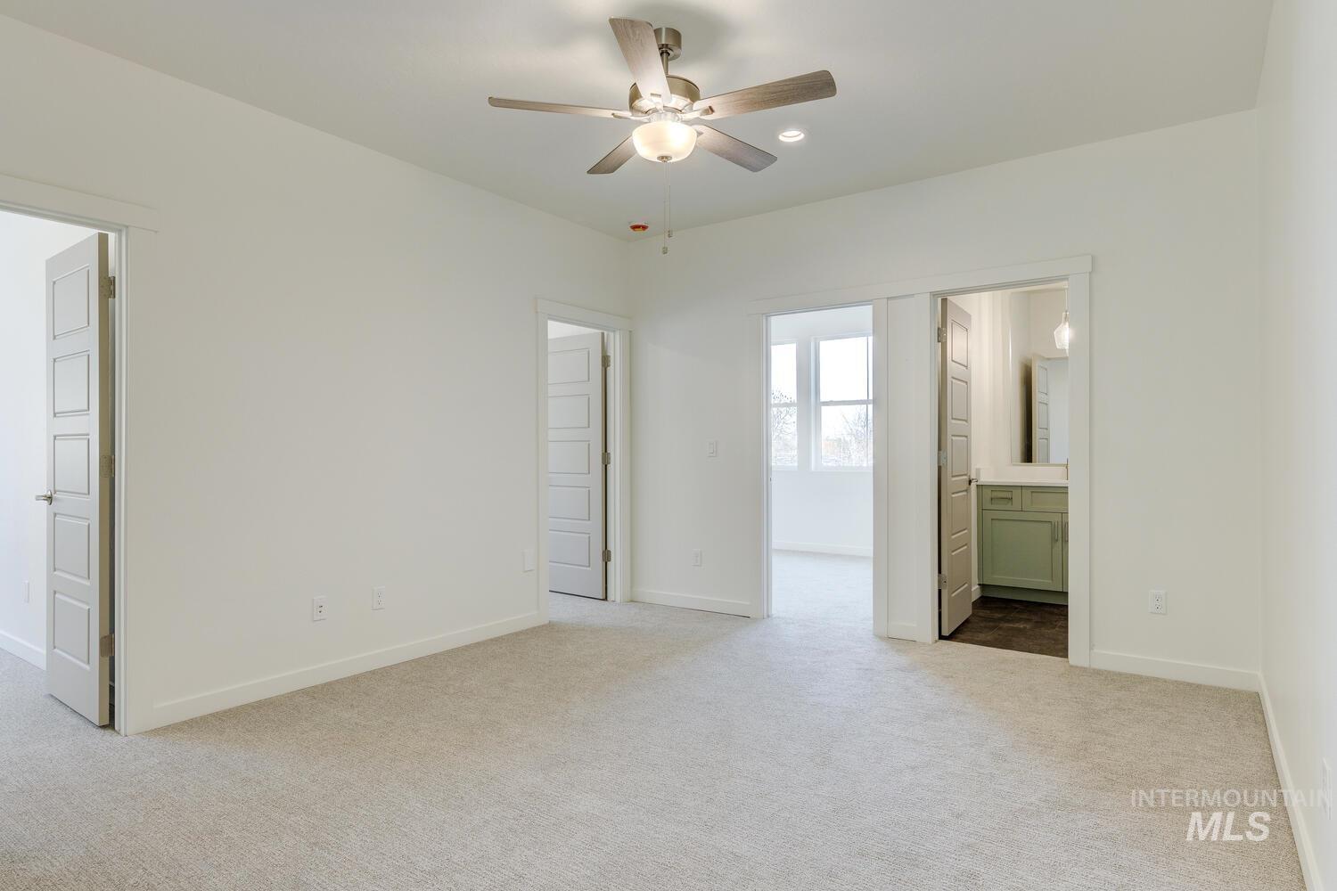 Unfurnished bedroom featuring ensuite bathroom, light carpet, and ceiling fan