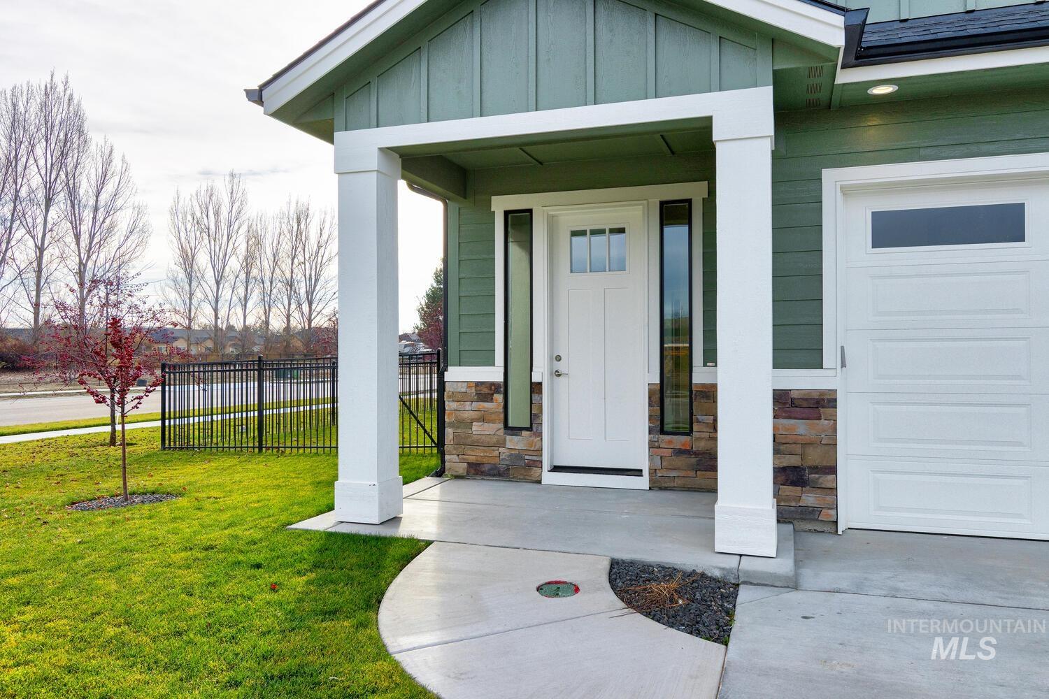 View of exterior entry with covered porch, board and batten siding, stone siding, and a water view