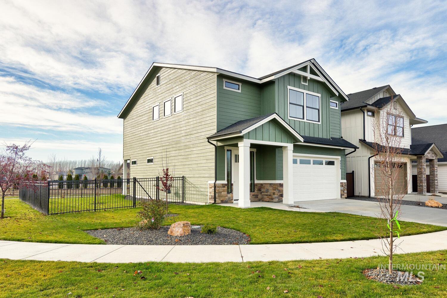 Craftsman-style house with board and batten siding, an attached garage, driveway, and stone siding