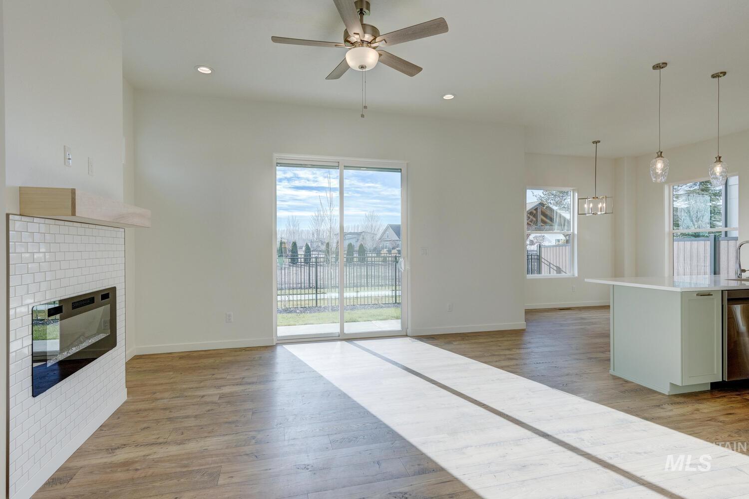 Unfurnished living room with light wood-type flooring, a glass covered fireplace, plenty of natural light, a ceiling fan, and recessed lighting