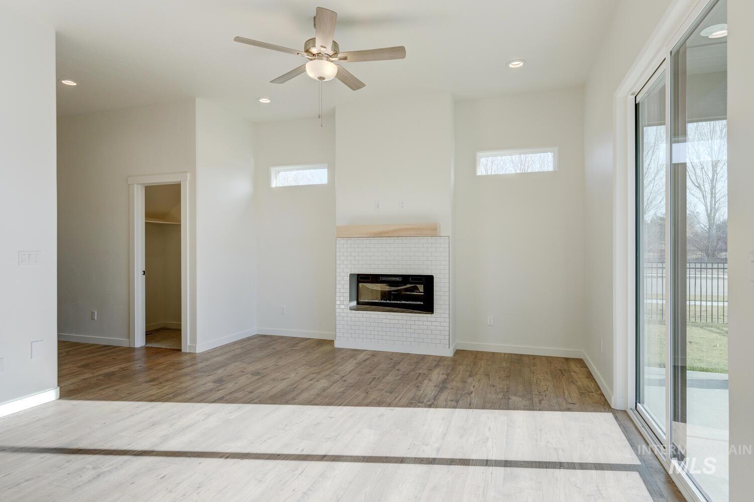 Unfurnished living room featuring light wood-type flooring, a brick fireplace, a ceiling fan, and recessed lighting