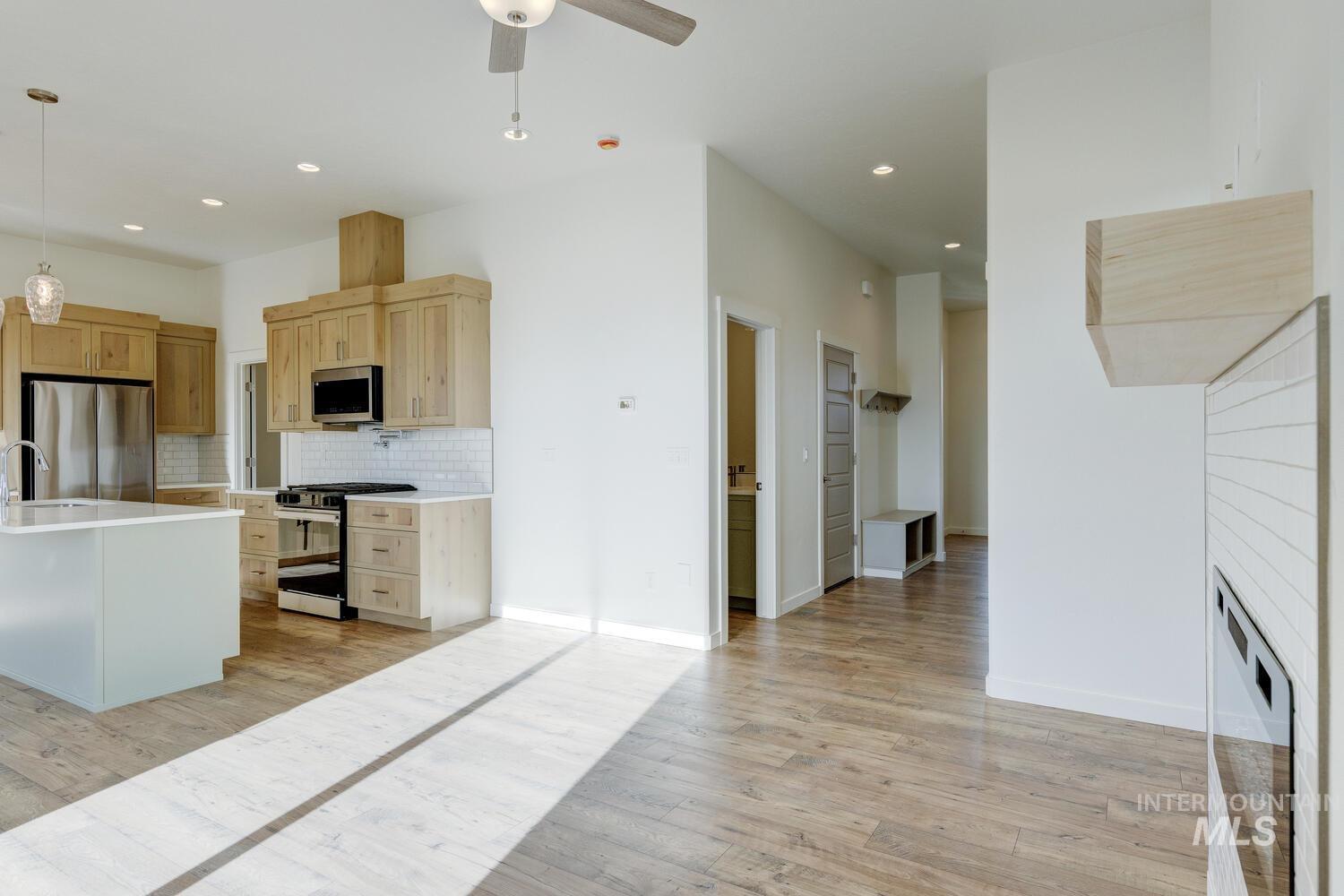Kitchen with hanging light fixtures, light wood finished floors, stainless steel appliances, tasteful backsplash, and recessed lighting