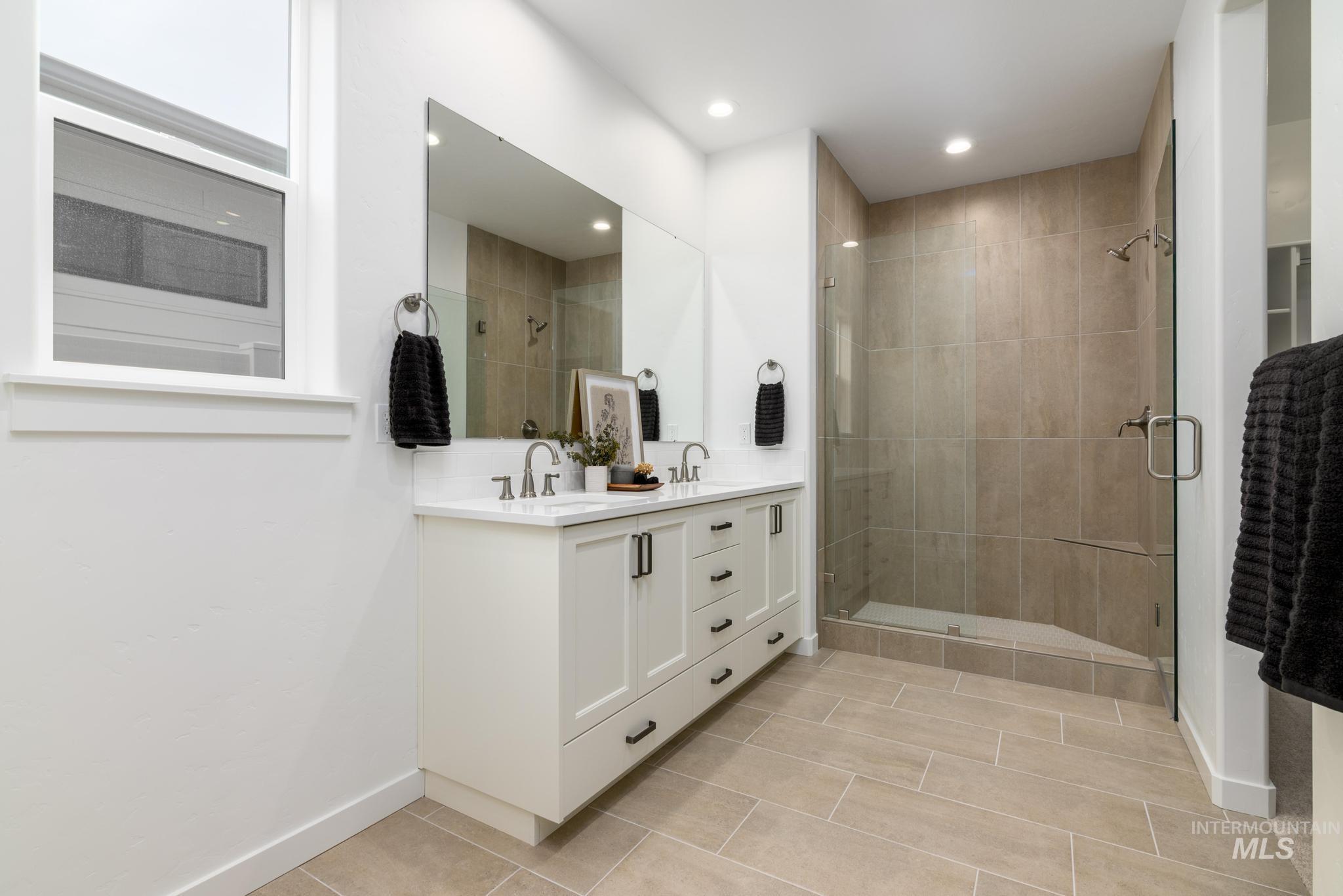 Full bathroom featuring double vanity, a shower stall, and light tile patterned flooring