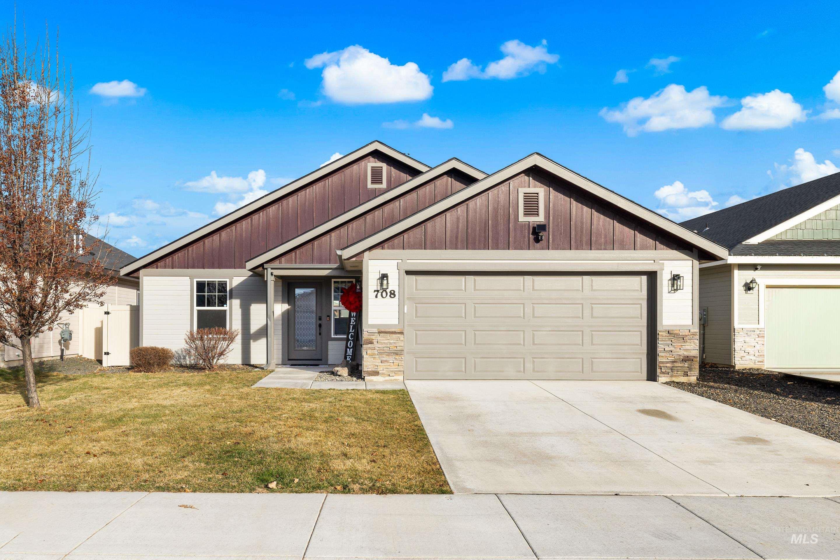 Craftsman inspired home with stone siding, a front yard, concrete driveway, and an attached garage
