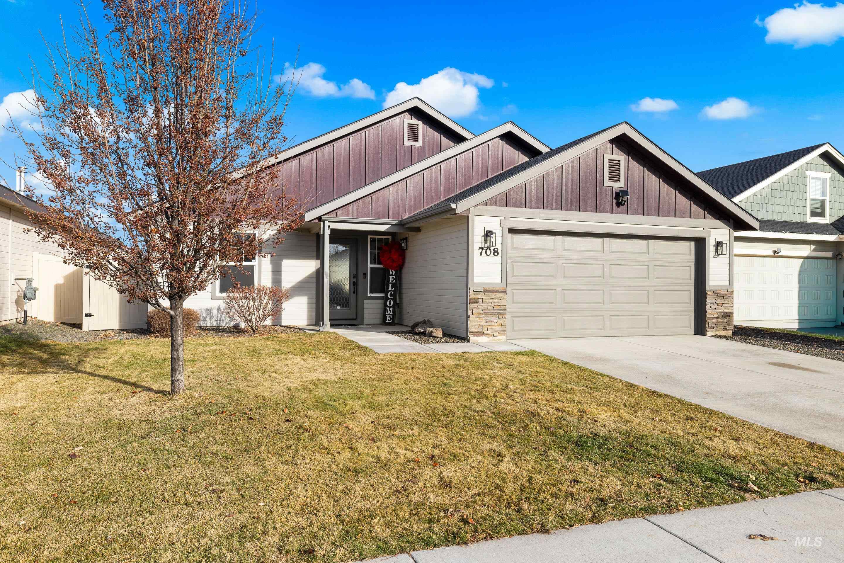 Craftsman-style house featuring a front lawn, concrete driveway, an attached garage, and stone siding