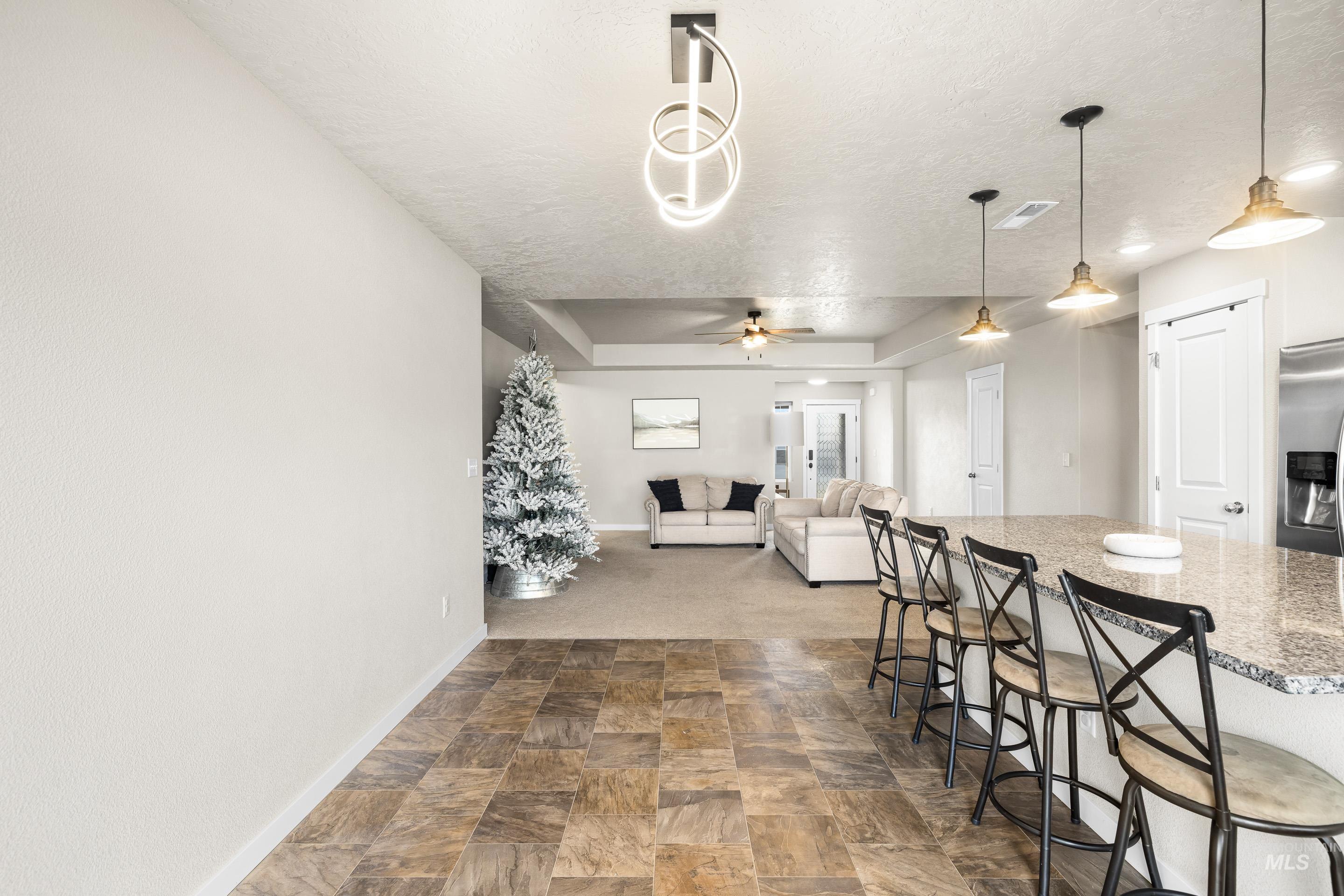 Dining area with a textured ceiling, stone finish floors, and ceiling fan