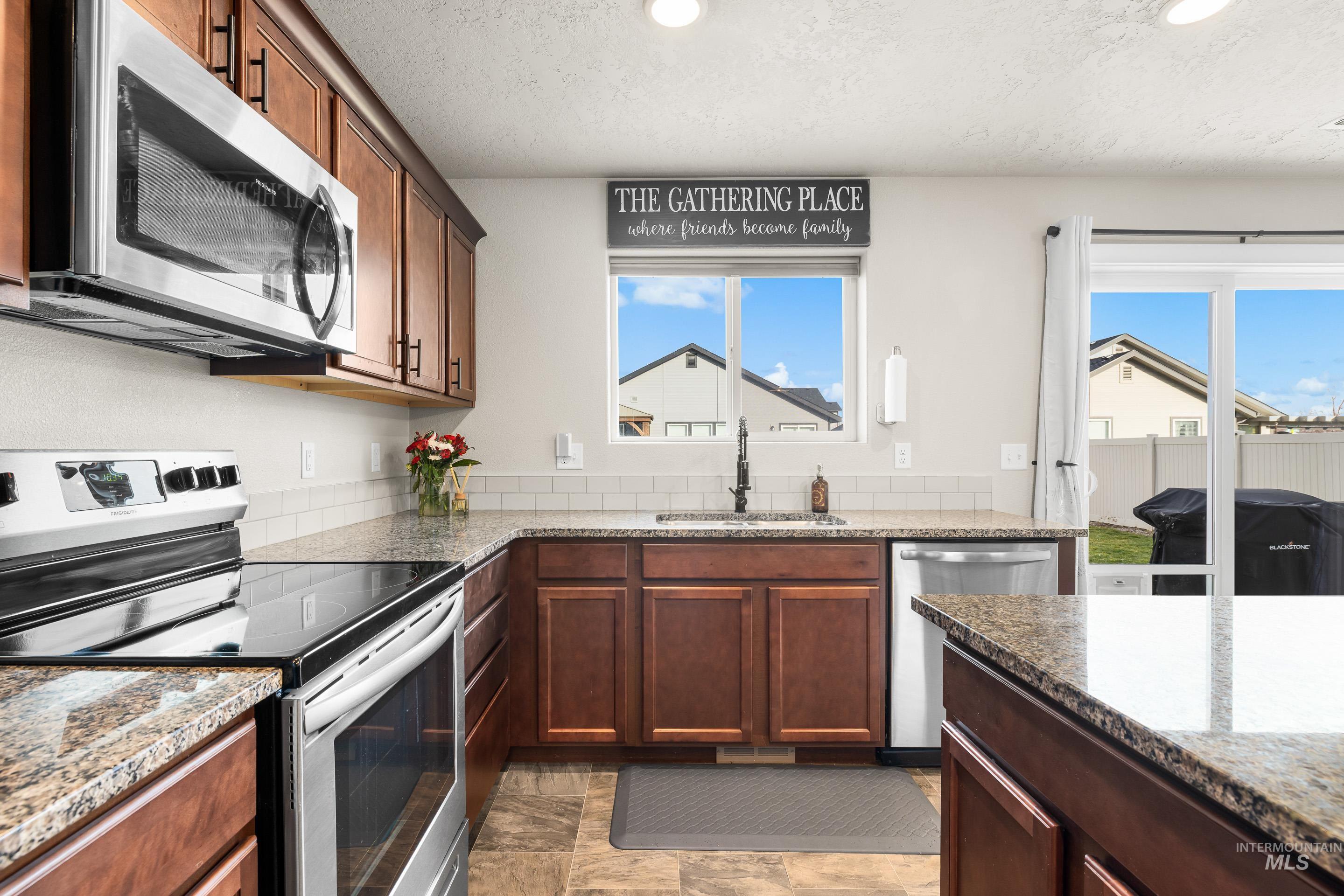 Kitchen featuring appliances with stainless steel finishes, dark stone counters, a textured ceiling, and recessed lighting
