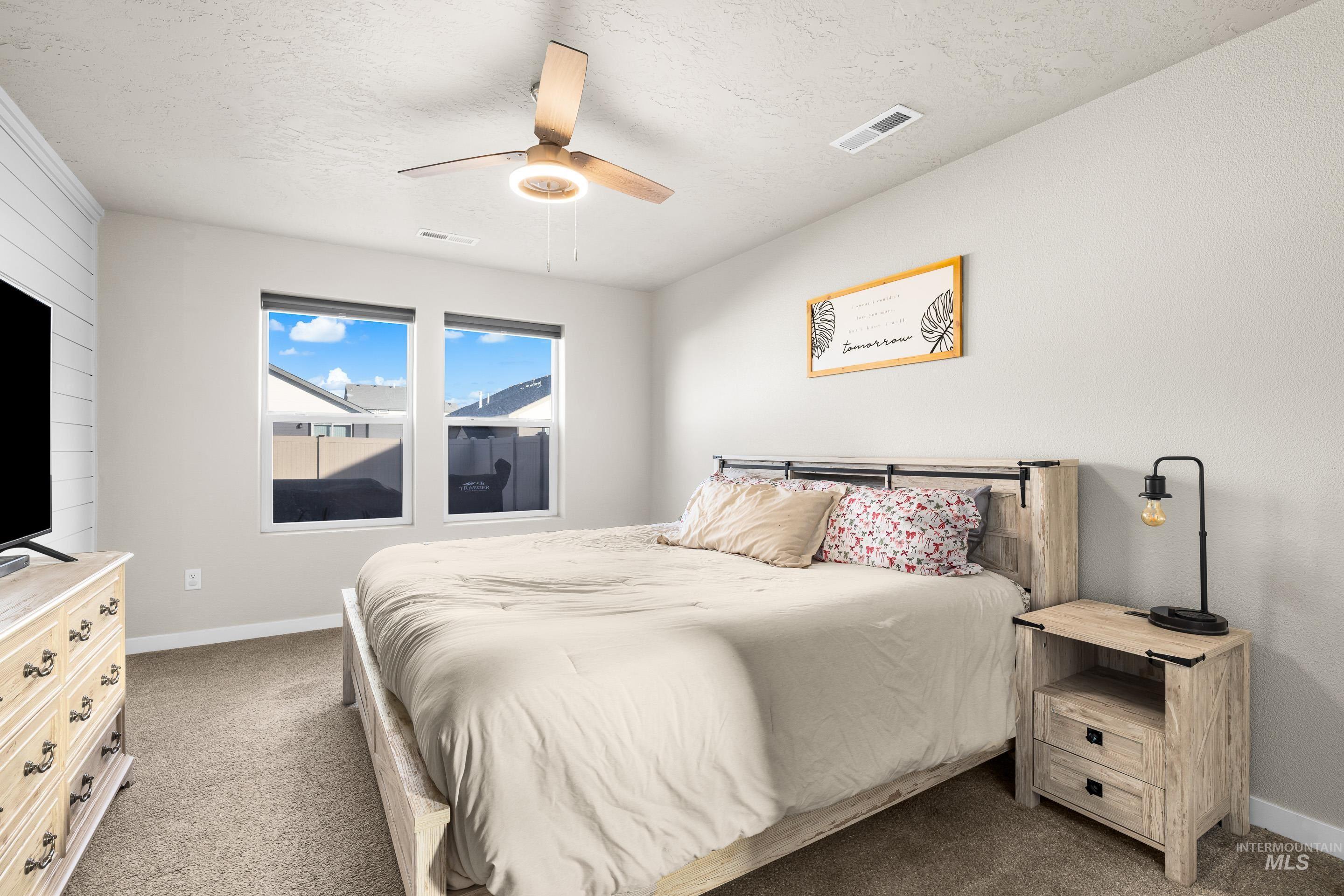 Bedroom with carpet, a ceiling fan, and a textured ceiling