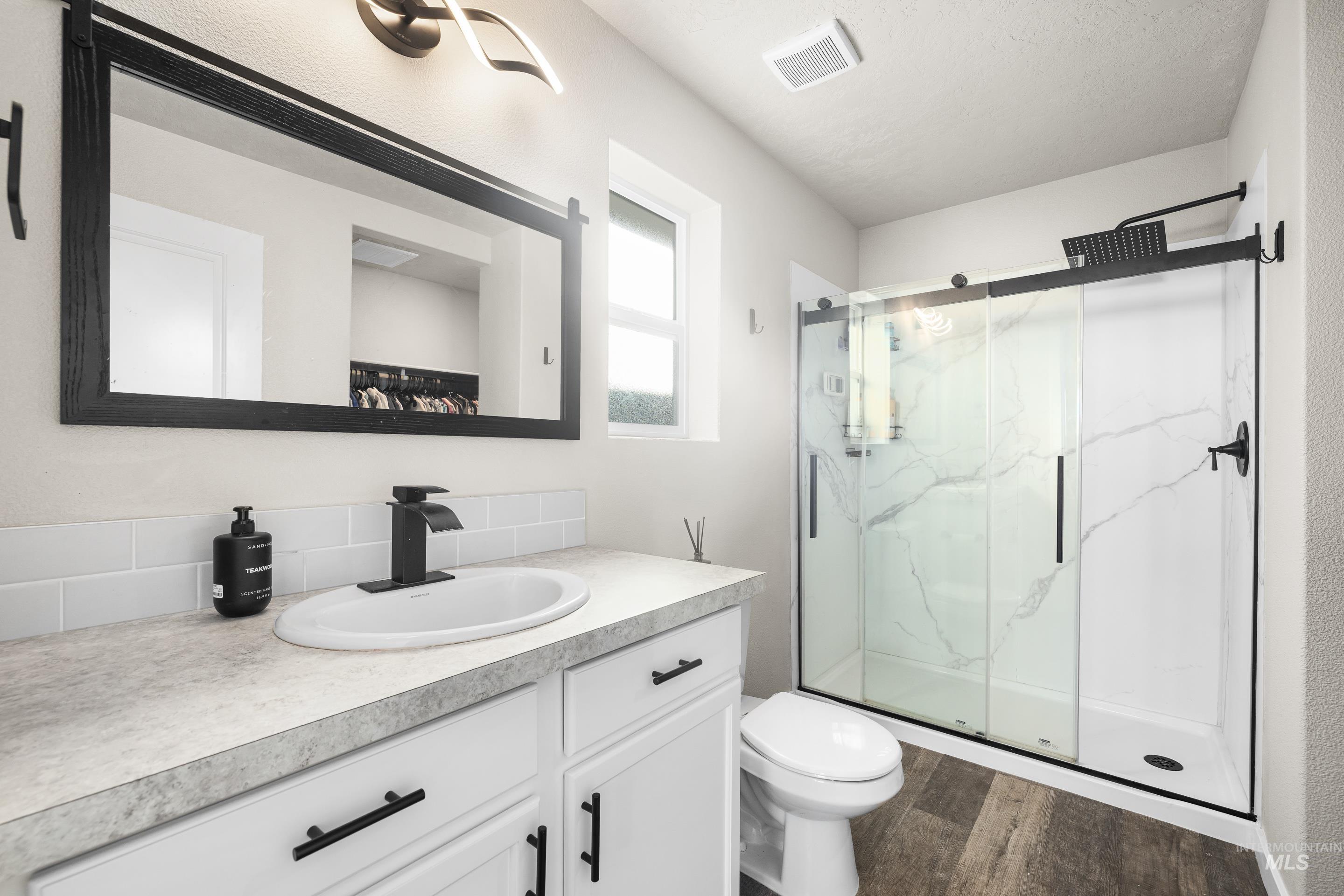 Bathroom featuring vanity, dark wood finished floors, and a marble finish shower