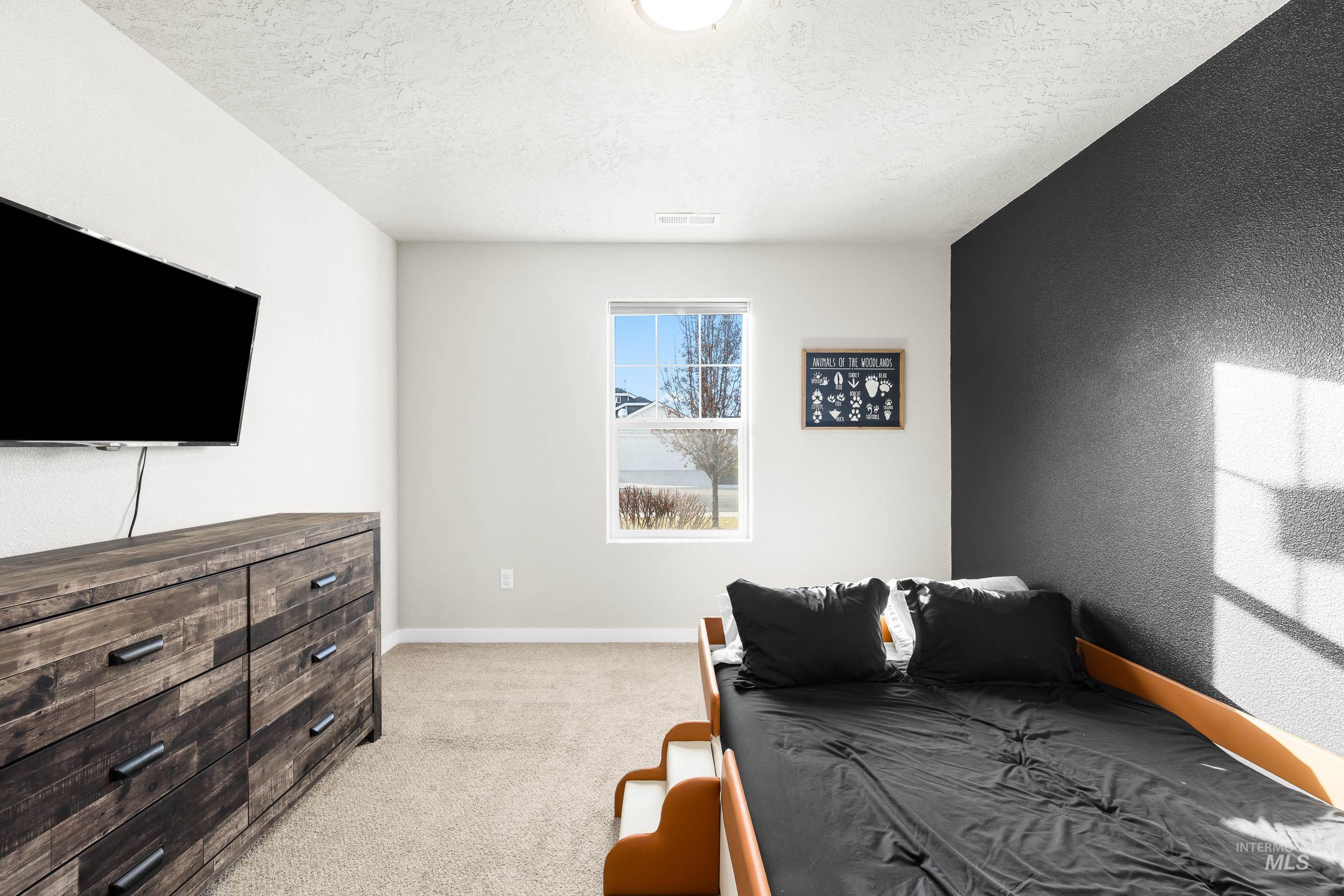 Bedroom featuring light colored carpet and a textured ceiling