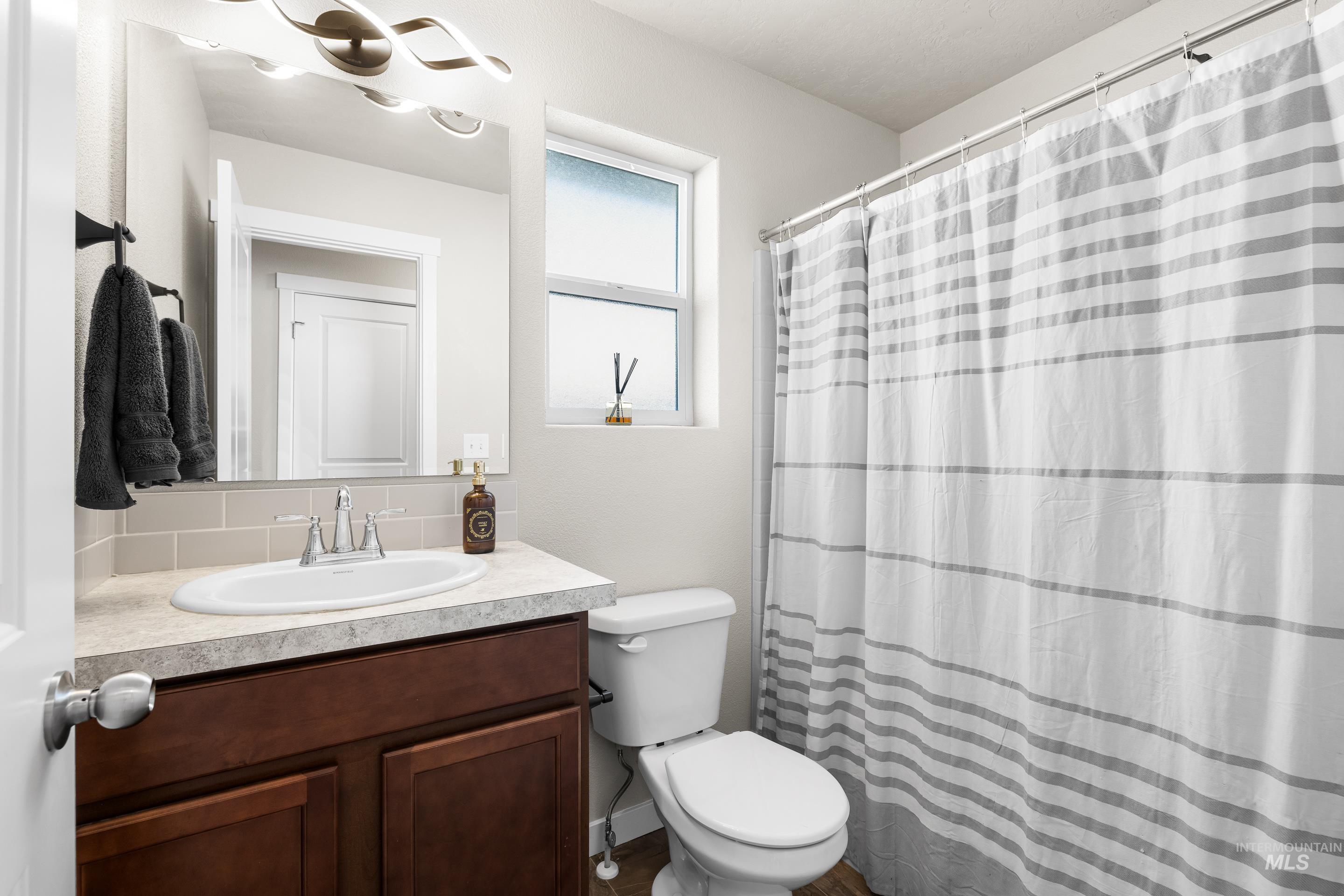 Bathroom with a shower with curtain, vanity, and backsplash