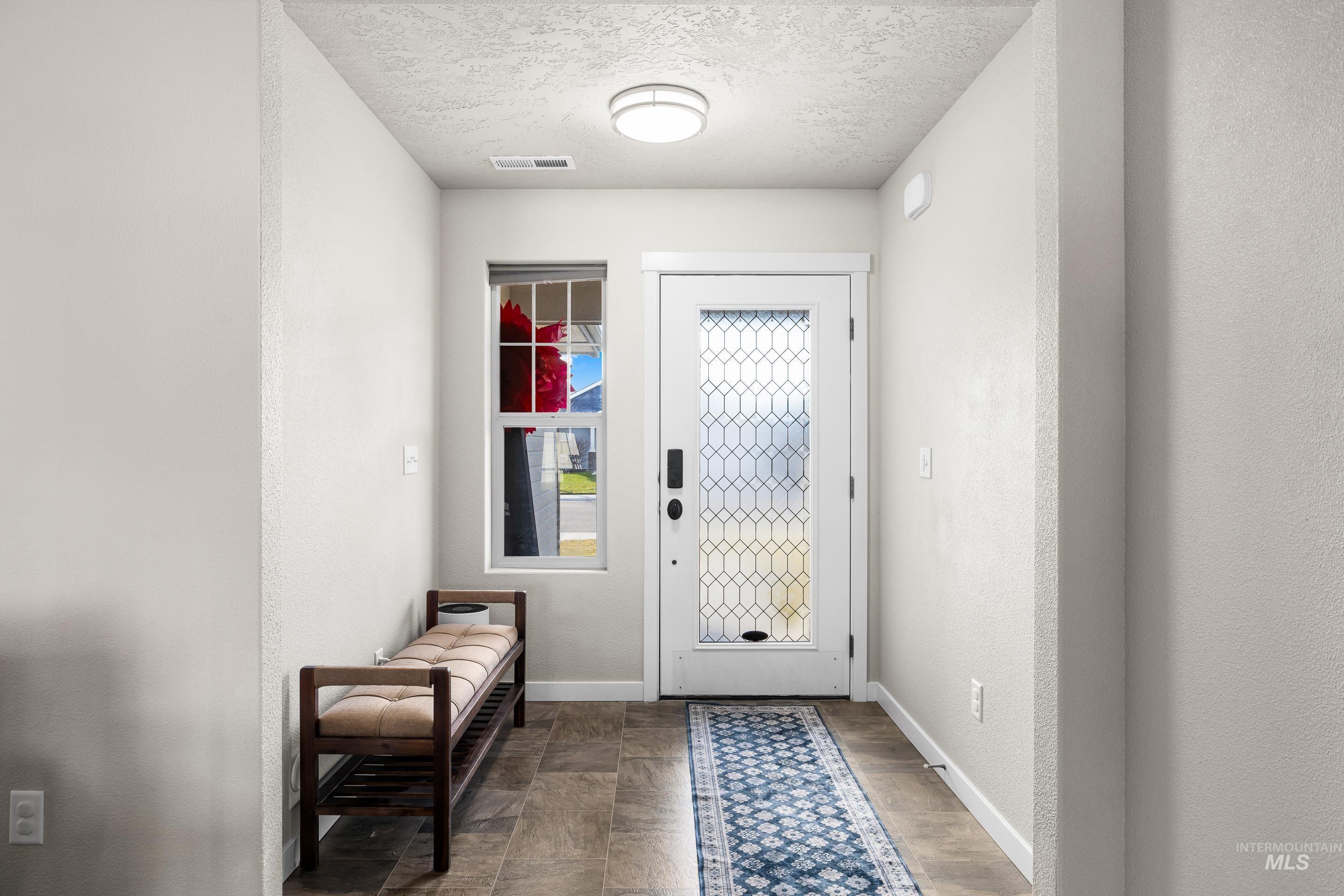 Entryway with a textured ceiling and a textured wall
