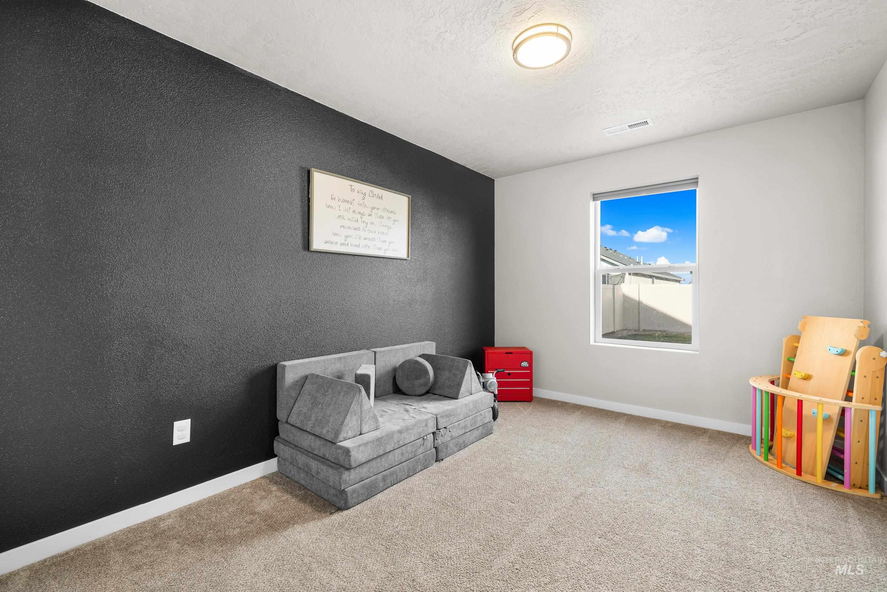 Recreation room with a textured ceiling, carpet, and a textured wall