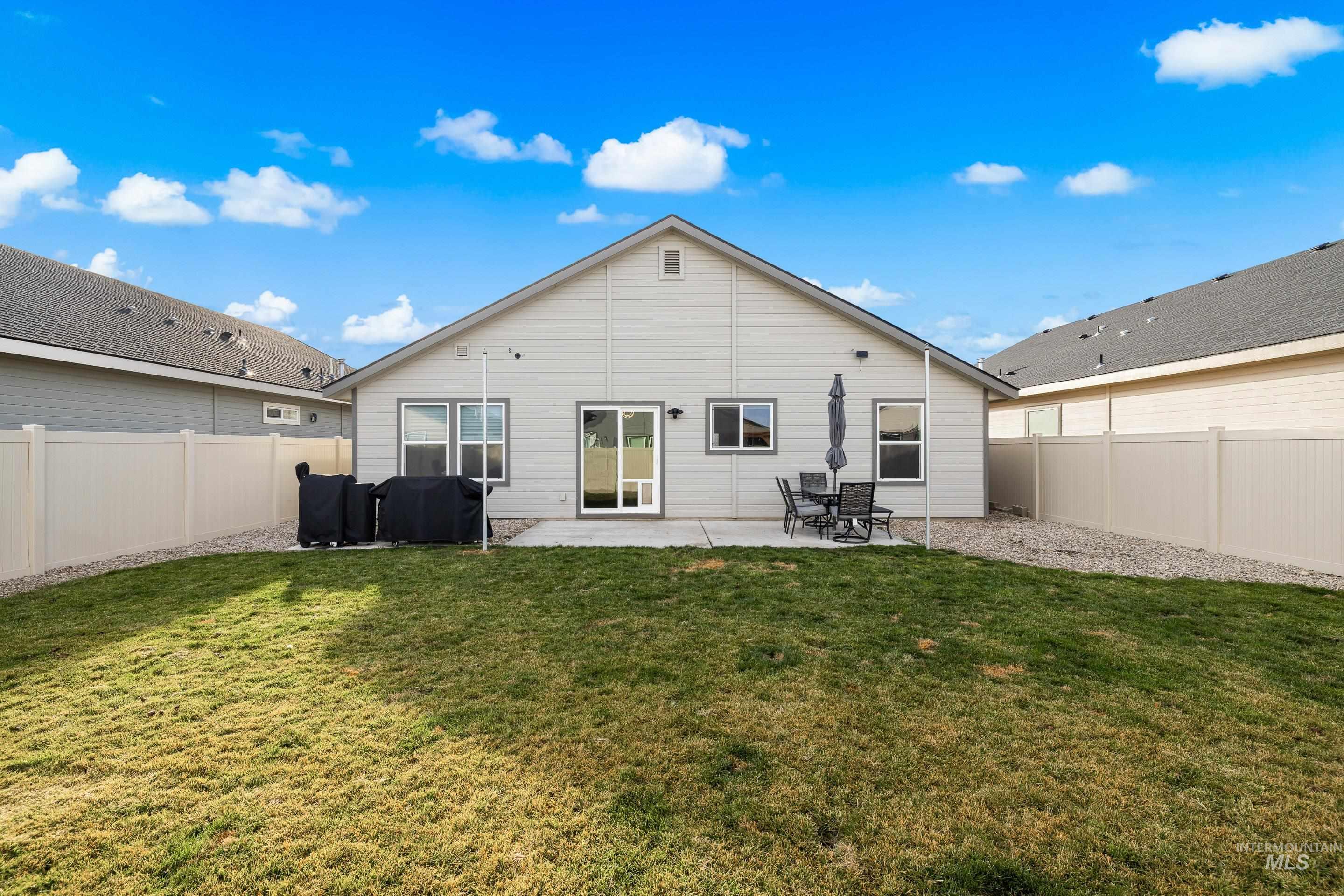 Rear view of property with a fenced backyard and a patio