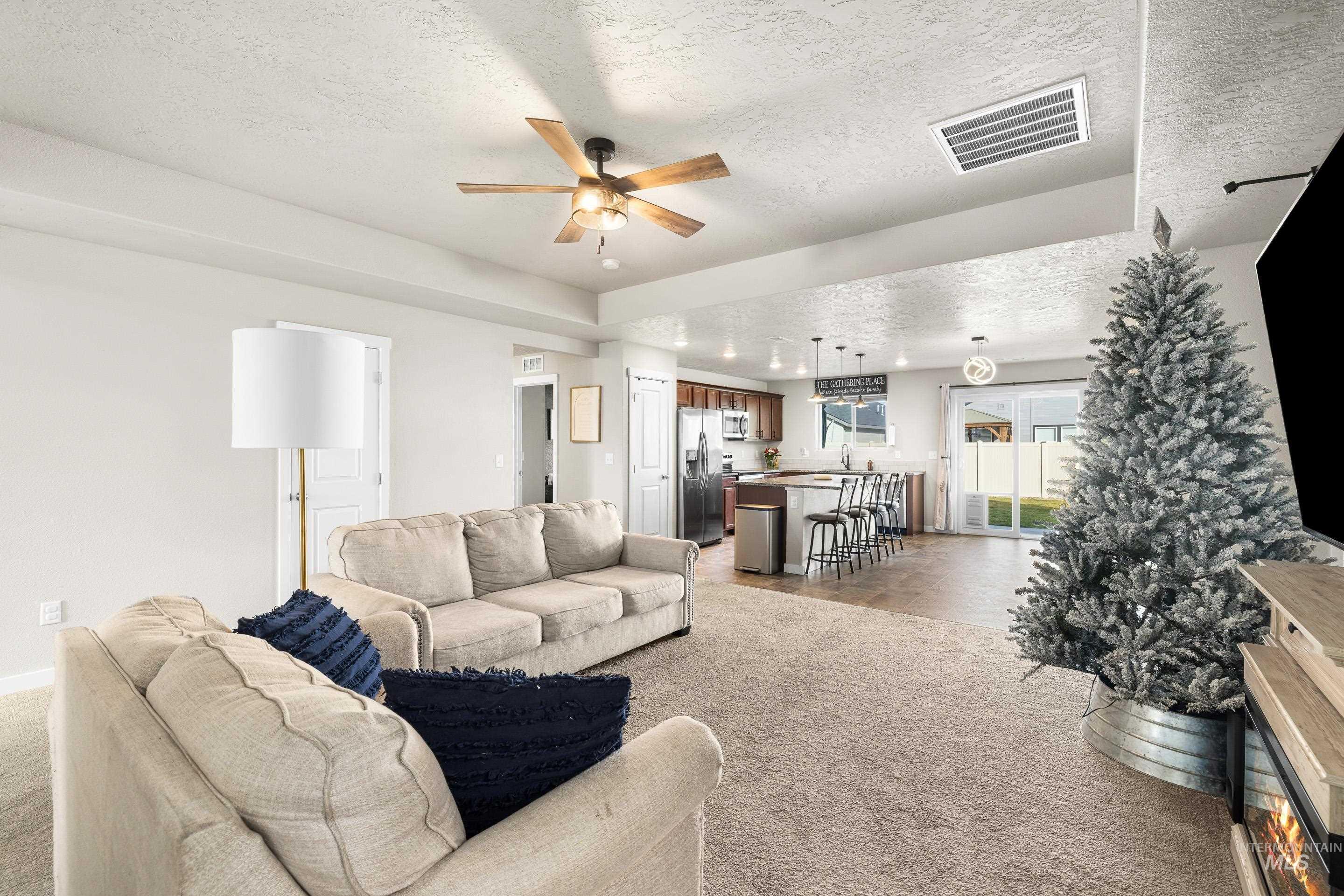 Living room featuring a textured ceiling, light carpet, and a ceiling fan