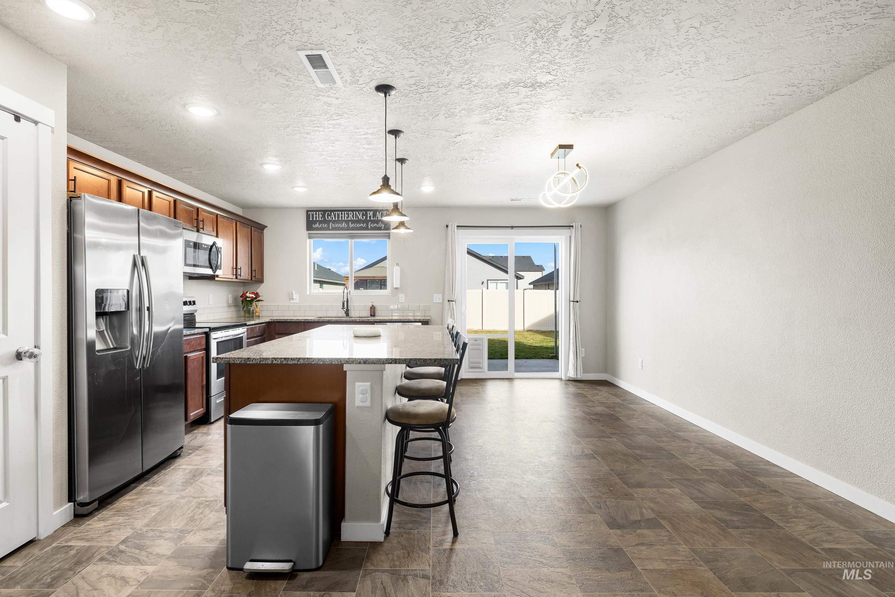 Kitchen featuring stainless steel appliances, a kitchen island, a kitchen breakfast bar, hanging light fixtures, and recessed lighting