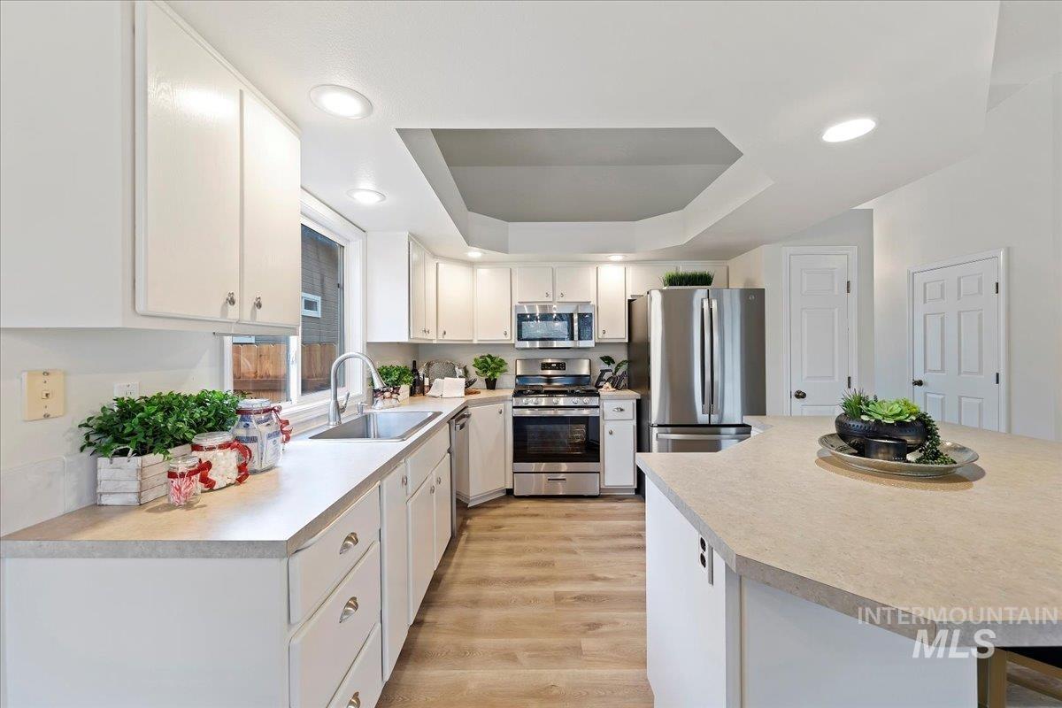 Kitchen featuring a Vaulted Ceiling w/suspended soffit, G.E. appliances with stainless steel finishes, NEW countertops, a center island, and recessed lighting