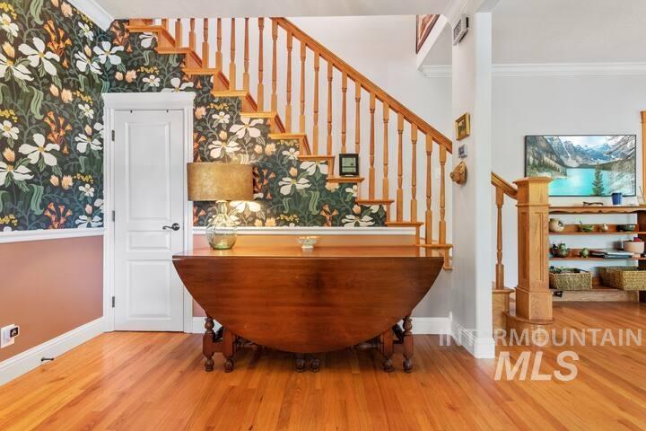 Bar with crown molding, light wood-style flooring, wallpapered walls, and stairs