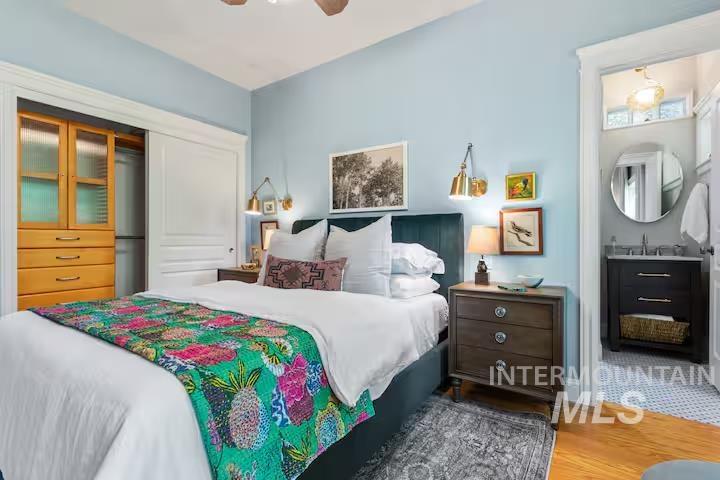 Bedroom with a closet, wood finished floors, connected bathroom, and a ceiling fan