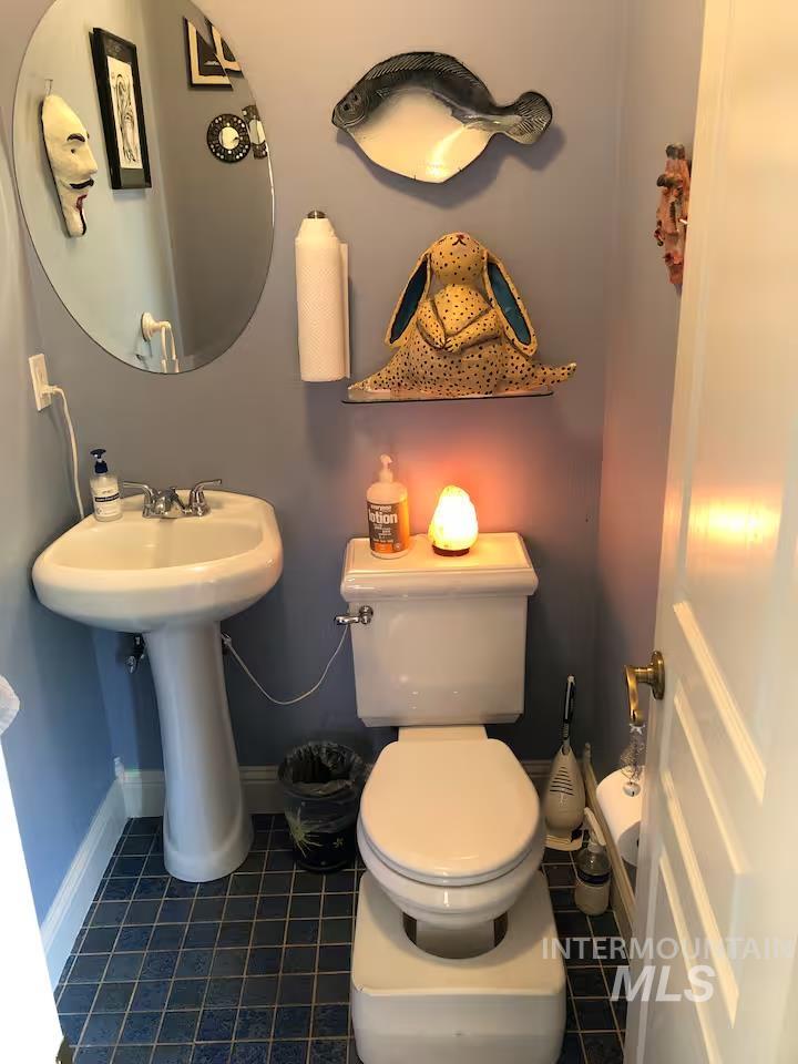 Half bathroom with toilet and dark tile patterned floors