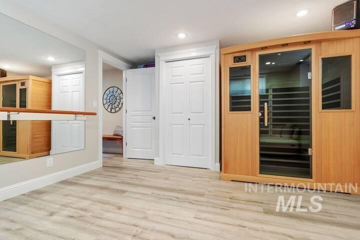 Interior space with glass insert cabinets, a sauna / steam room, light wood-style floors, and recessed lighting