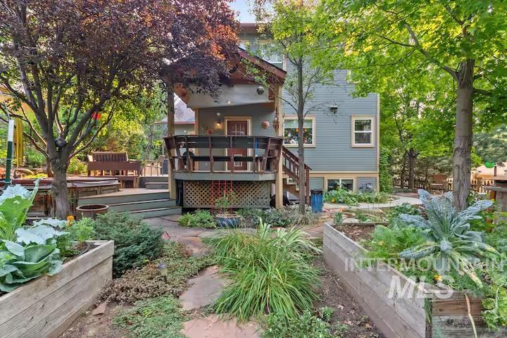 Back of property with a vegetable garden, a deck, and stairs