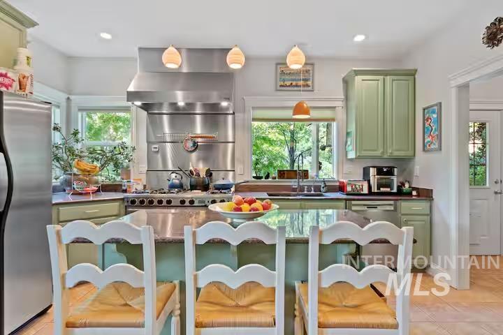 Kitchen with green cabinetry, stainless steel appliances, wall chimney exhaust hood, plenty of natural light, and recessed lighting