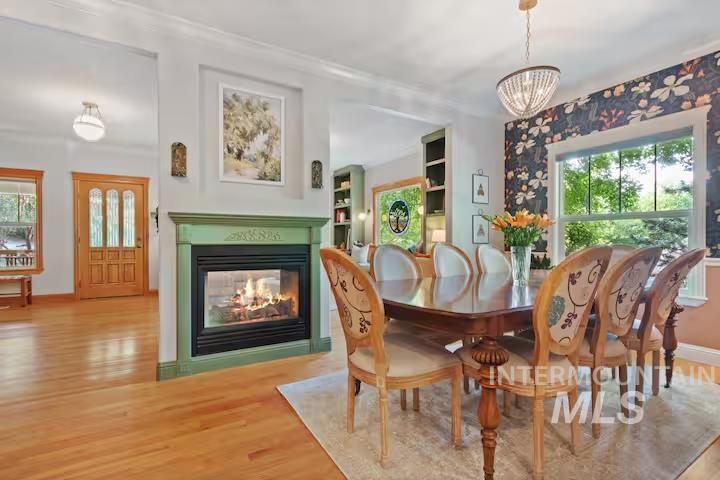 Dining room featuring wood finished floors, a multi sided fireplace, and a chandelier