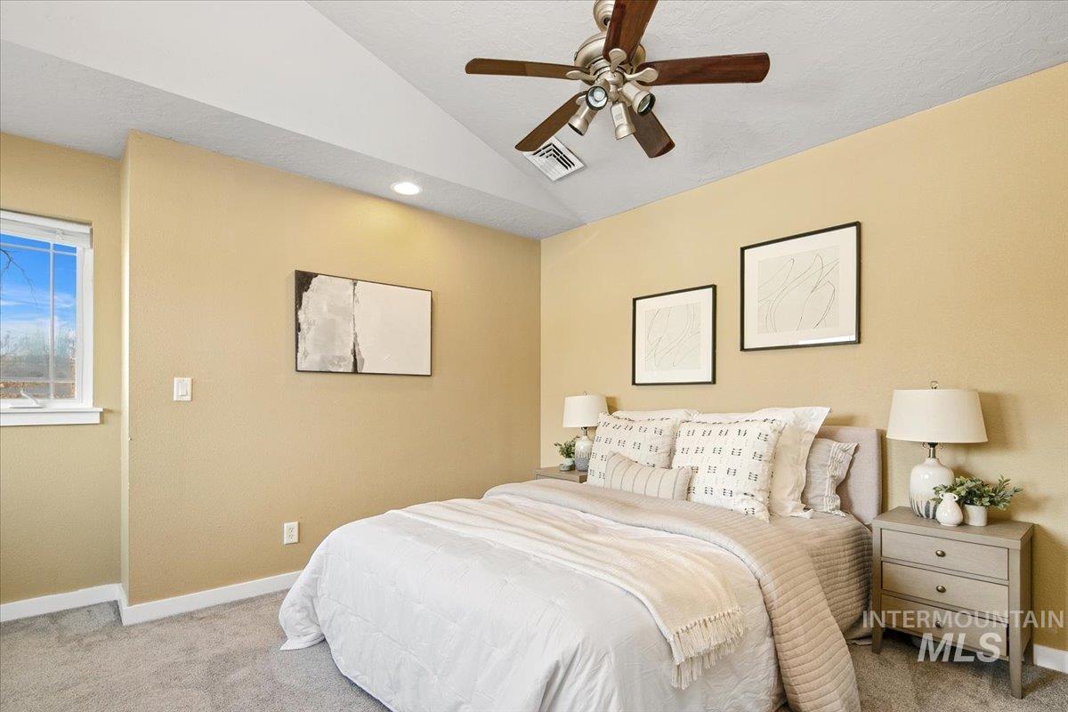 Primary Bedroom with vaulted ceiling, carpet, and a ceiling fan
