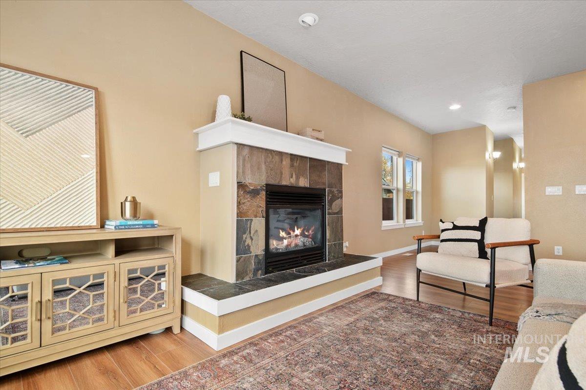 Living area with LVP floors, a tiled fireplace, and recessed lighting