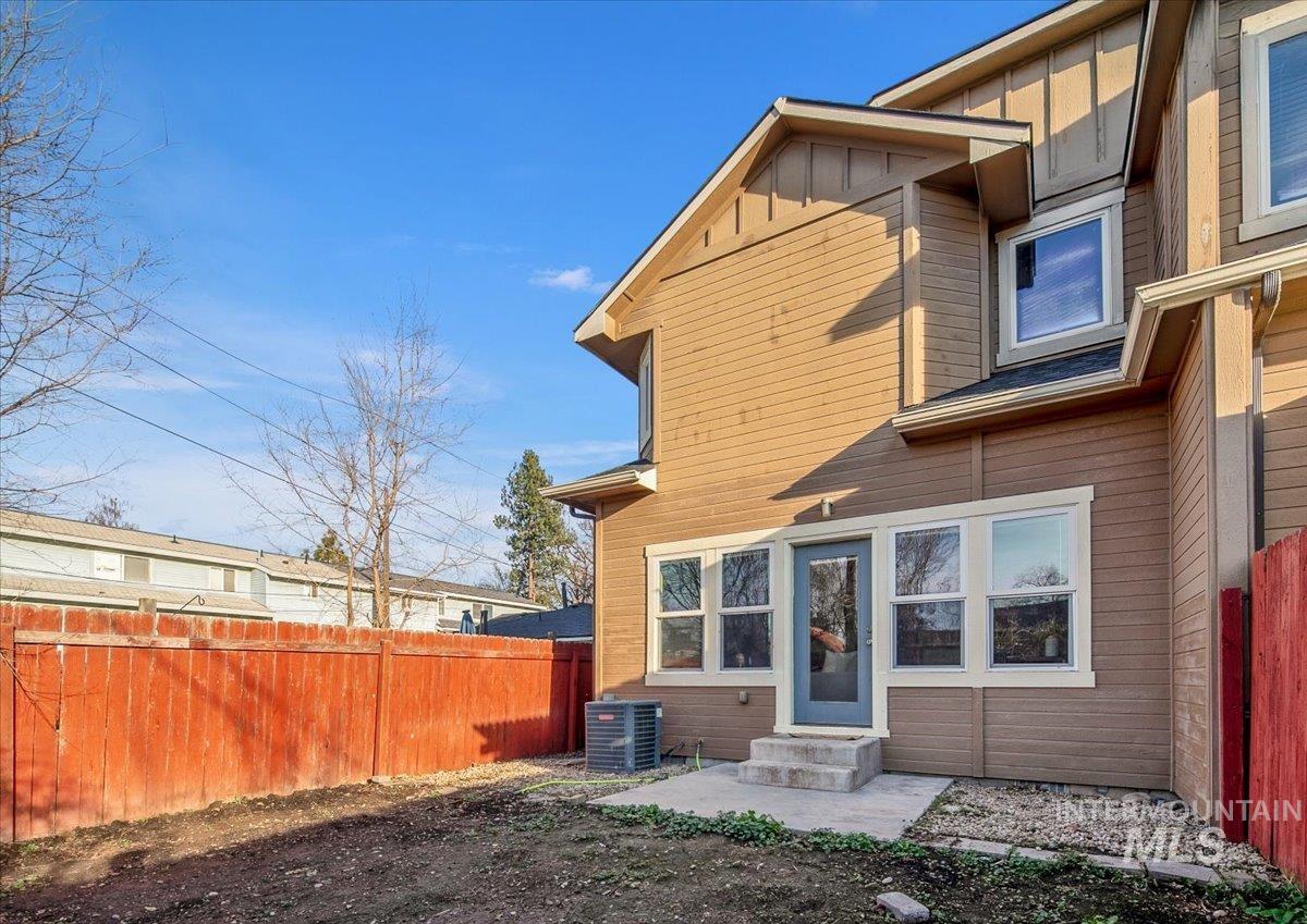 Rear view of property featuring a fenced backyard, entry steps, and board and batten siding