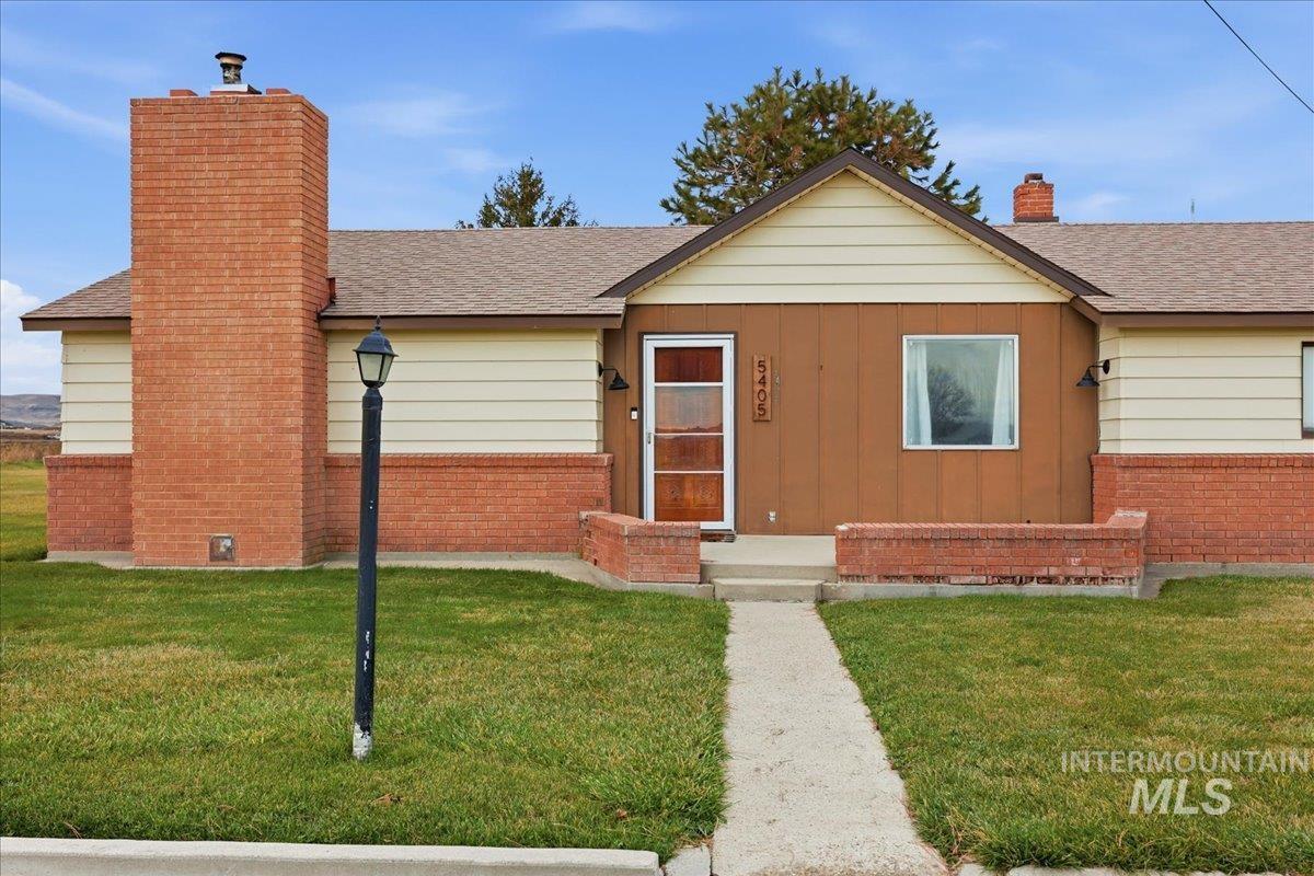 View of front of house with a chimney, roof with shingles, and a front yard